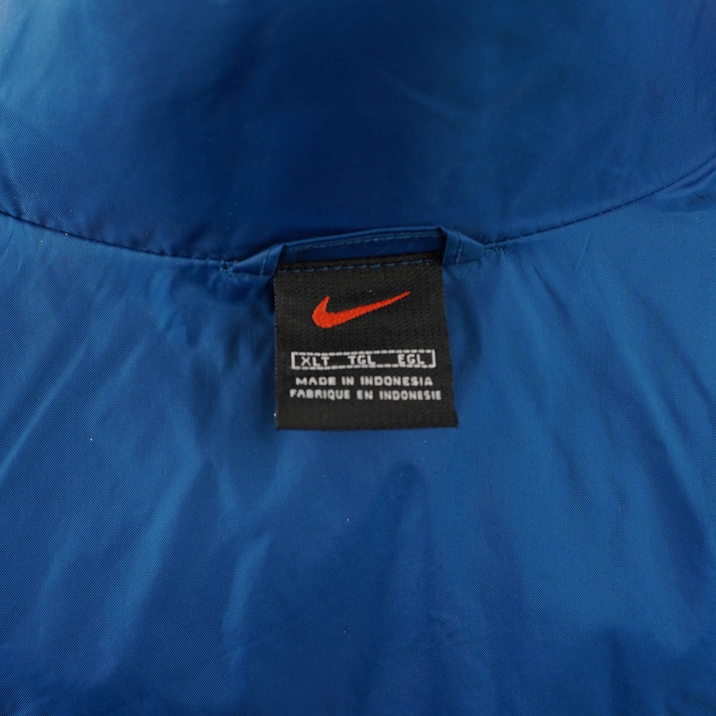 Etichetta quadrata nera Nike con Swoosh arancione cucita sul colletto interno che indica la taglia XLT.