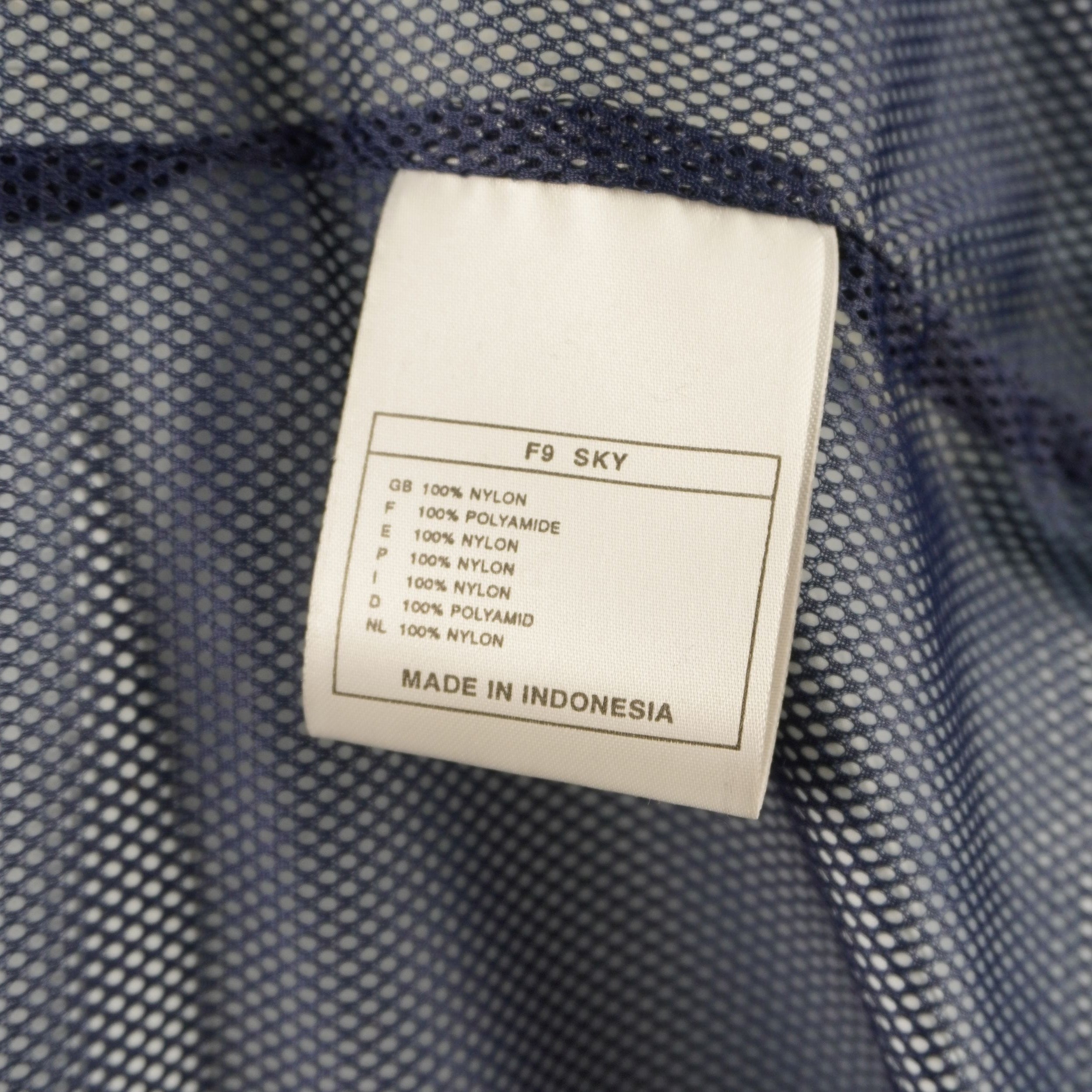 Tag interno bianco in tessuto con le istruzioni di lavaggio e l'indicazione di manifattura Made in Indonesia.
