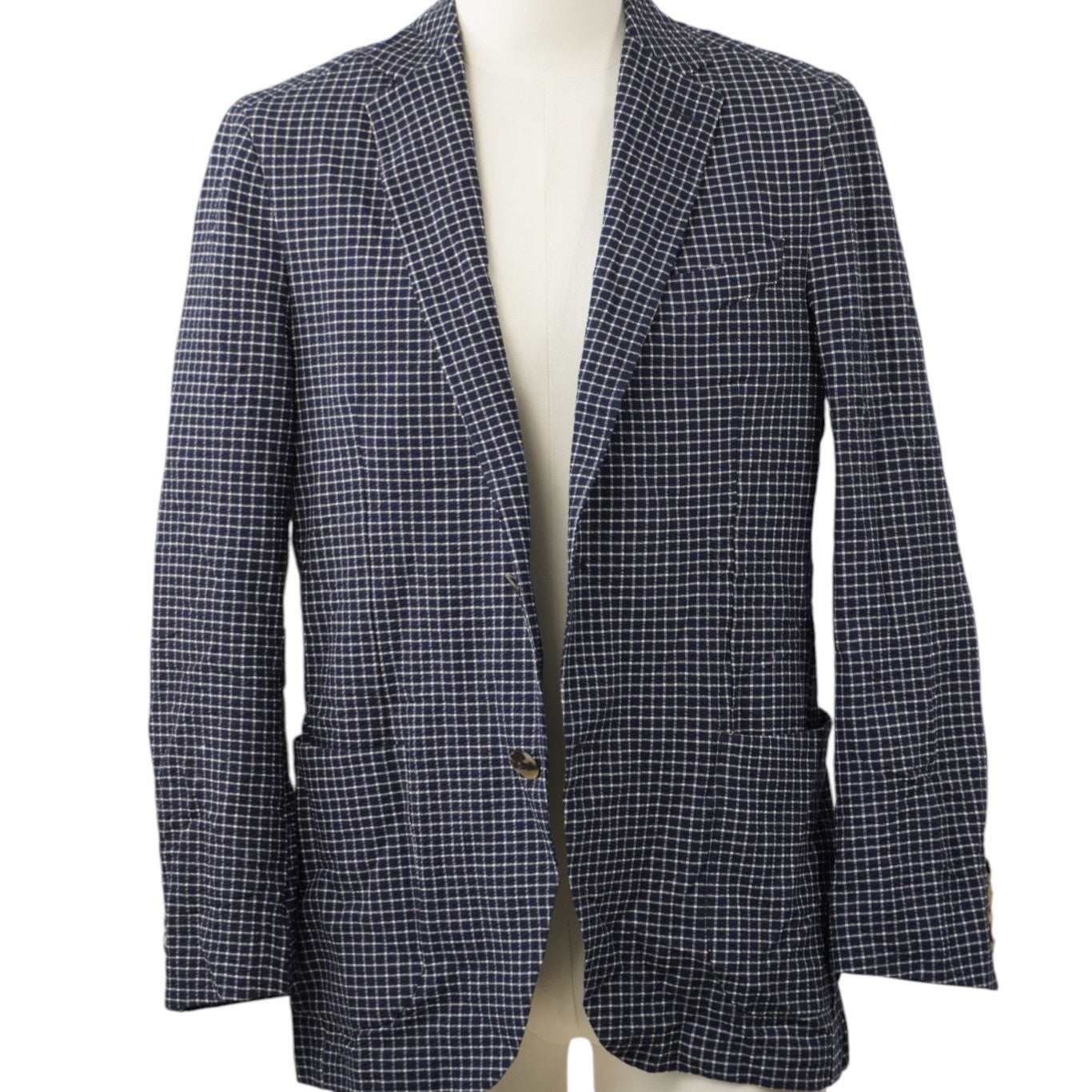 Vista frontale su manichino di una giacca monopetto Etro Milano a micro-quadretti blu e bianchi con tasche a toppa frontali.