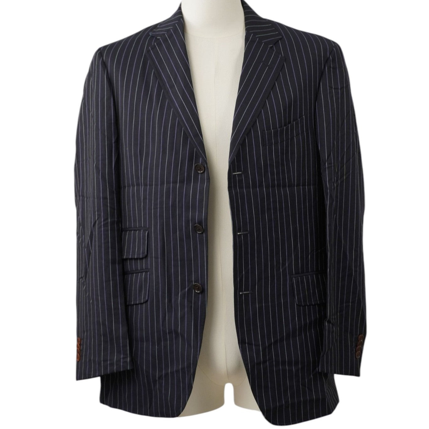 Vista frontale su manichino di una giacca monopetto gessata Etro Milano in lana blu navy con tasche a filetto e patta frontali.