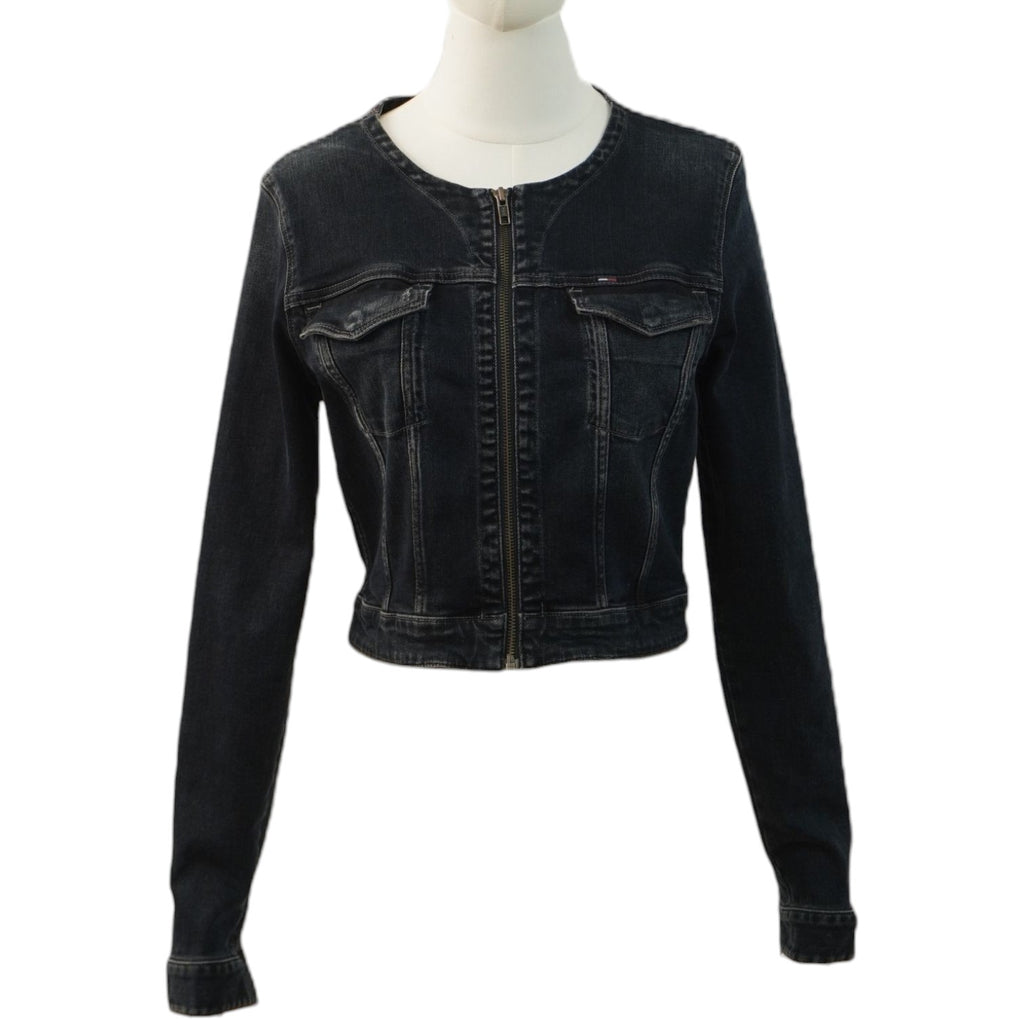 Vista frontale di una giacca di jeans corta in denim nero lavato Tommy Hilfiger su un manichino, con chiusura lampo centrale e senza colletto.
