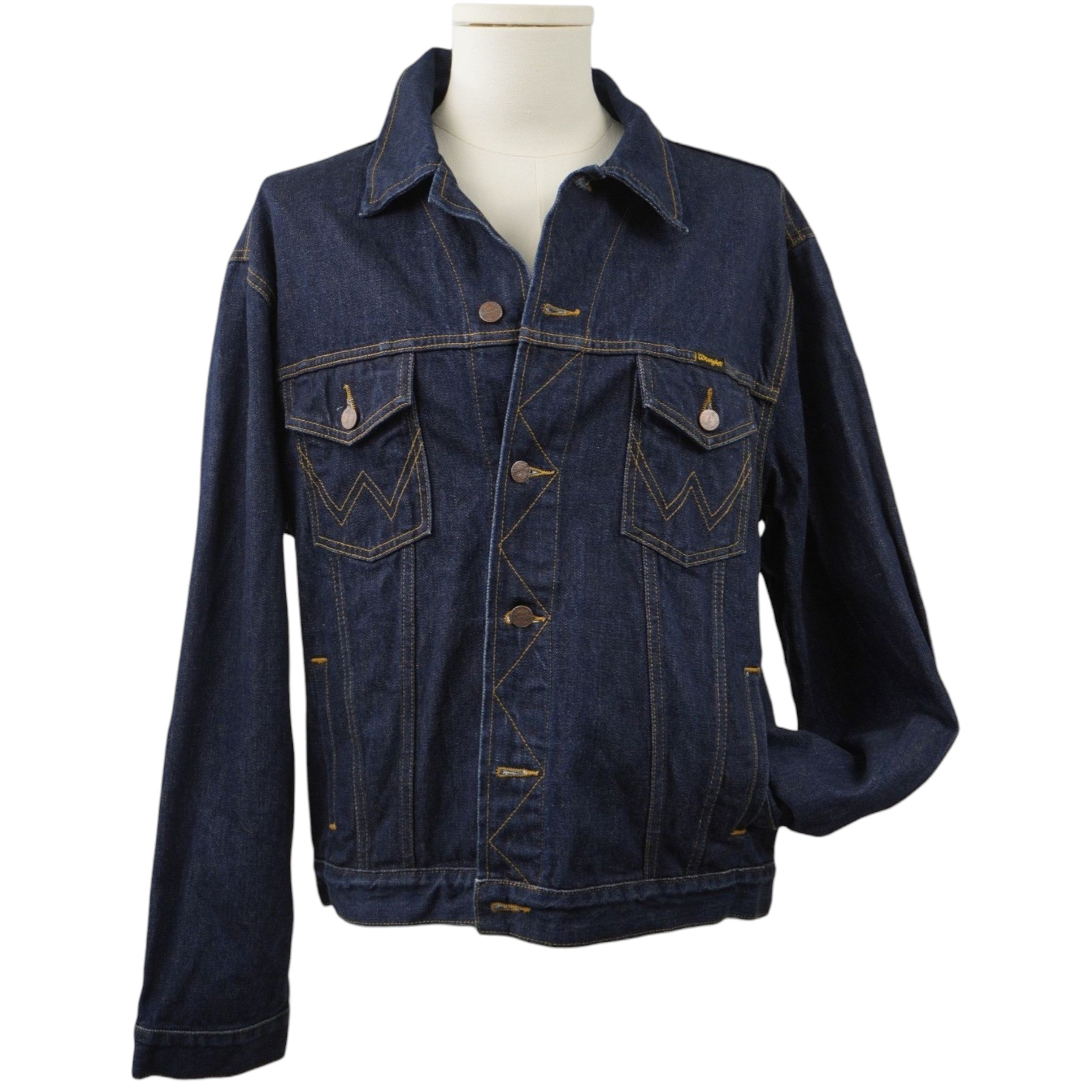 Vista frontale di una giacca di jeans Wrangler vintage color blu indaco scuro su manichino, con due tasche sul petto e cuciture color tabacco.