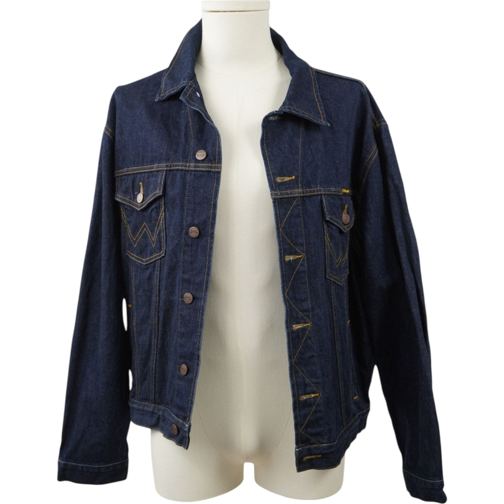 Vista frontale della giacca denim Wrangler indossata aperta su un manichino chiaro, che mostra la vestibilità del modello trucker.