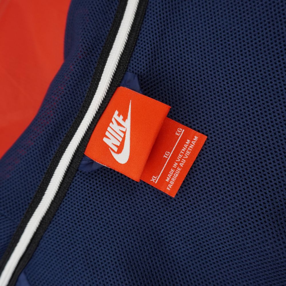 Primo piano dell'etichetta interna arancione Nike Sportswear cucita sul colletto che indica la taglia Extra Large XL.