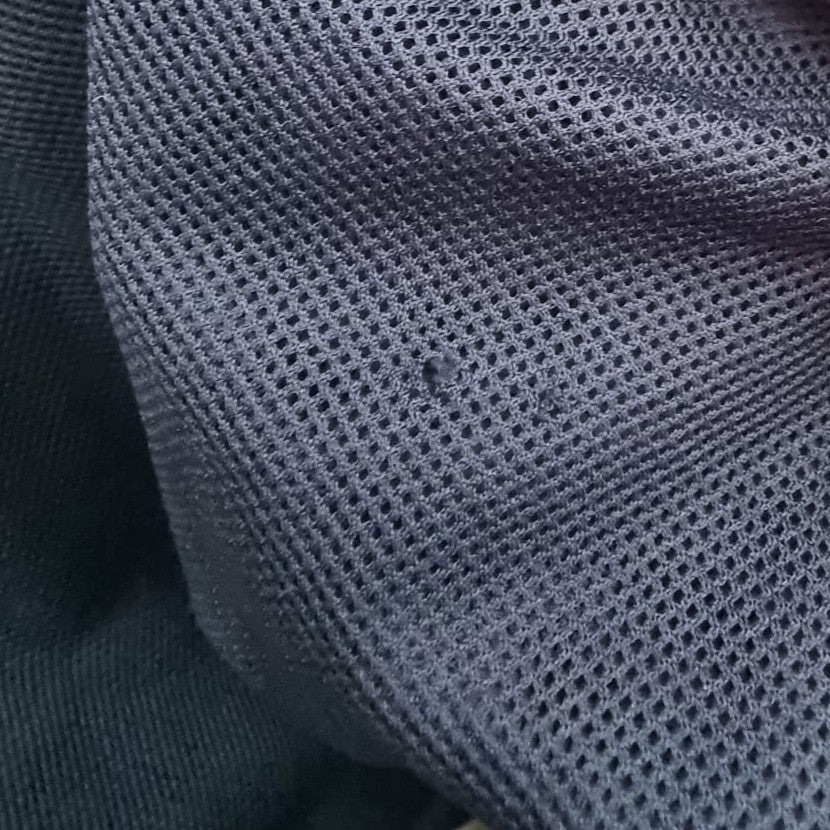Dettaglio di un piccolo foro superficiale da utilizzo localizzato sulla trama a rete della fodera interna in mesh blu navy.