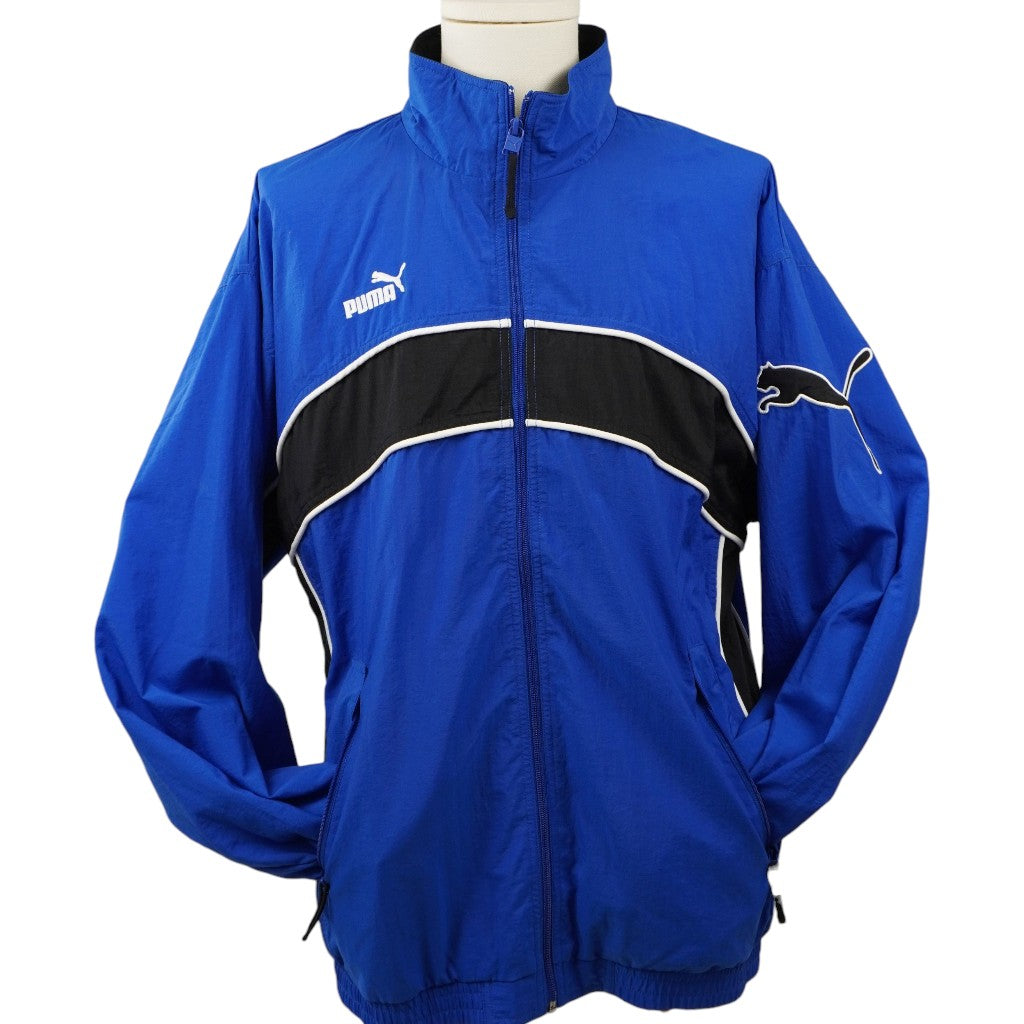 Vista frontale della track jacket Puma vintage blu e nera con chiusura a zip e loghi ricamati.