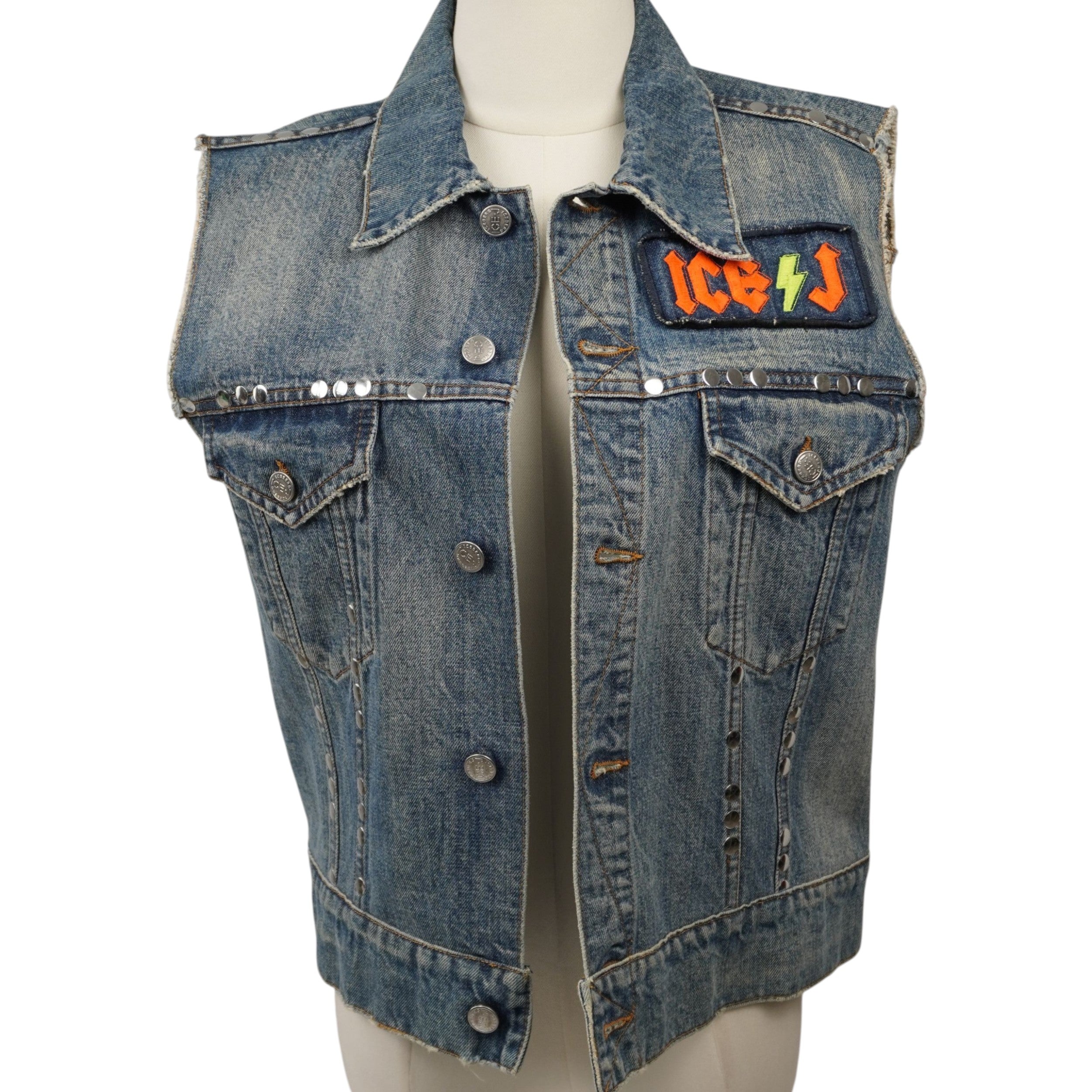 Gilet vintage in denim ICE-J Iceberg con borchie argentate e patch ricamata colorata sul petto, vista frontale su manichino.