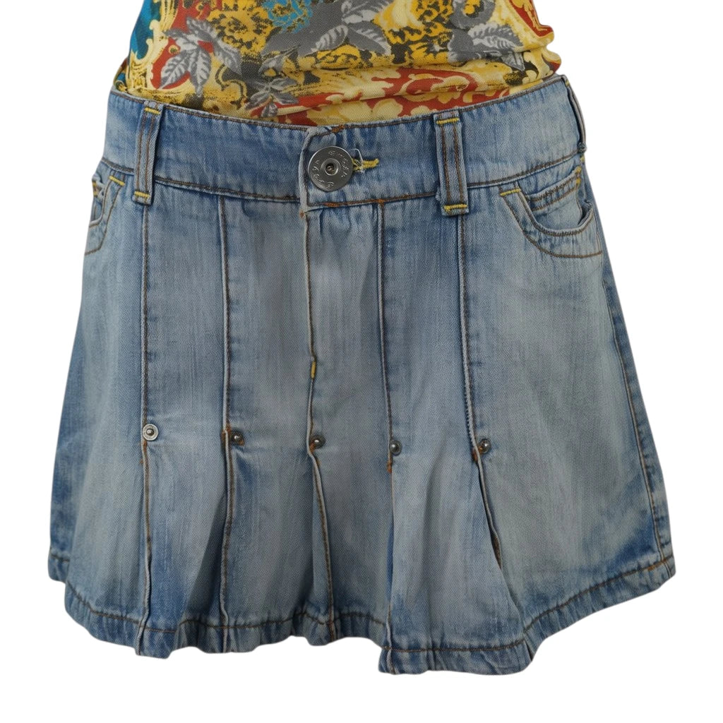  Inquadratura frontale della minigonna plissettata in denim chiaro d'archivio Extyn Denim con borchie metalliche.