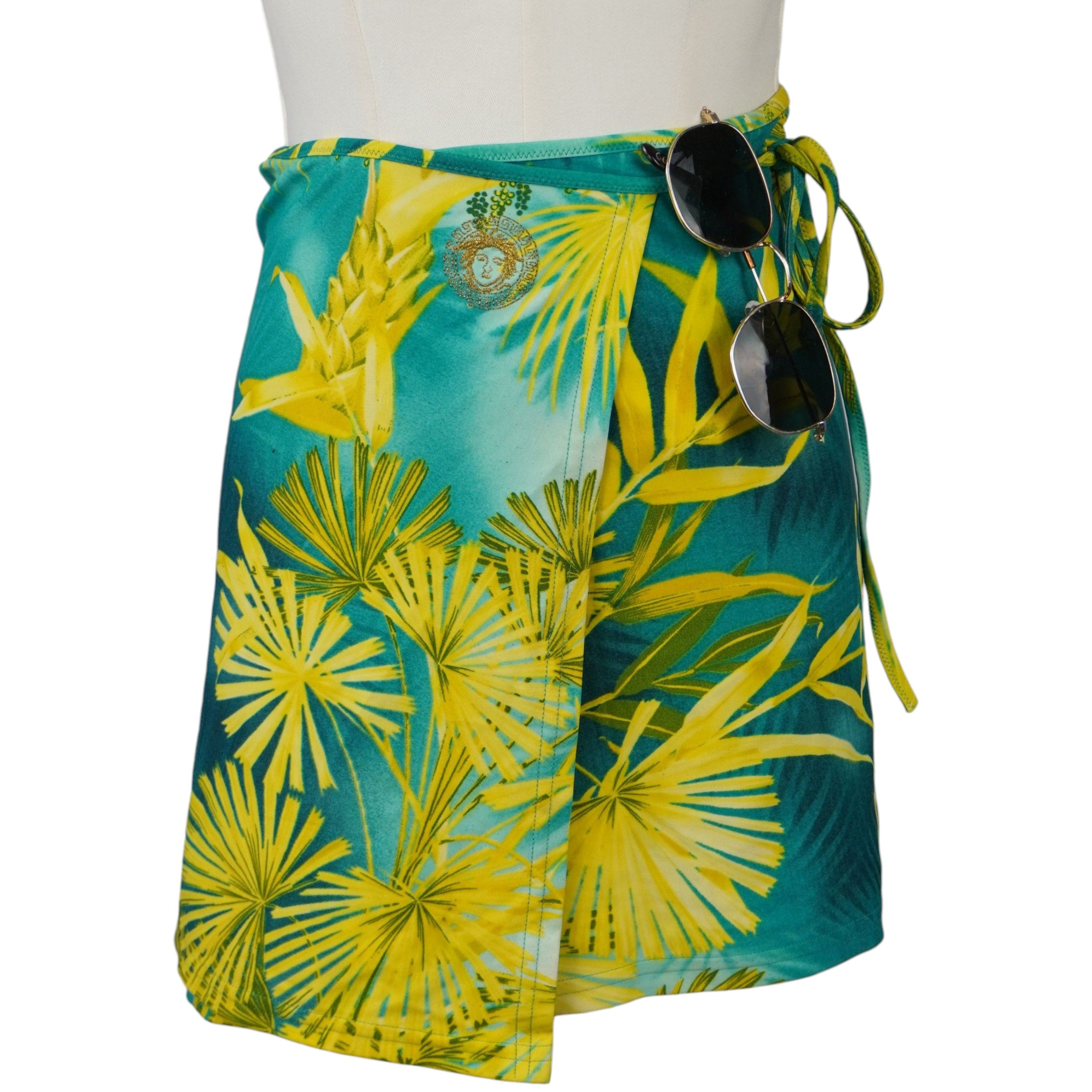 Vista frontale della gonna pareo corta a portafoglio Versace Mare con stampa tropicale gialla e verde.