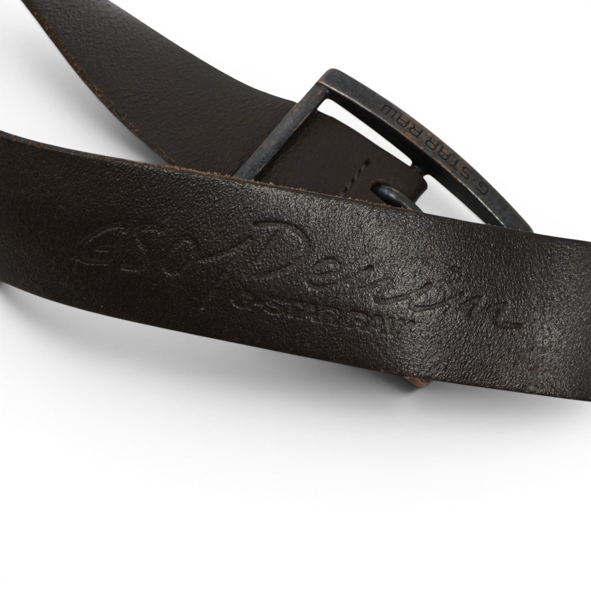 Particolare dell'incisione a caldo con scritta GS-Raw Denim impressa sulla superficie in pelle marrone scuro.