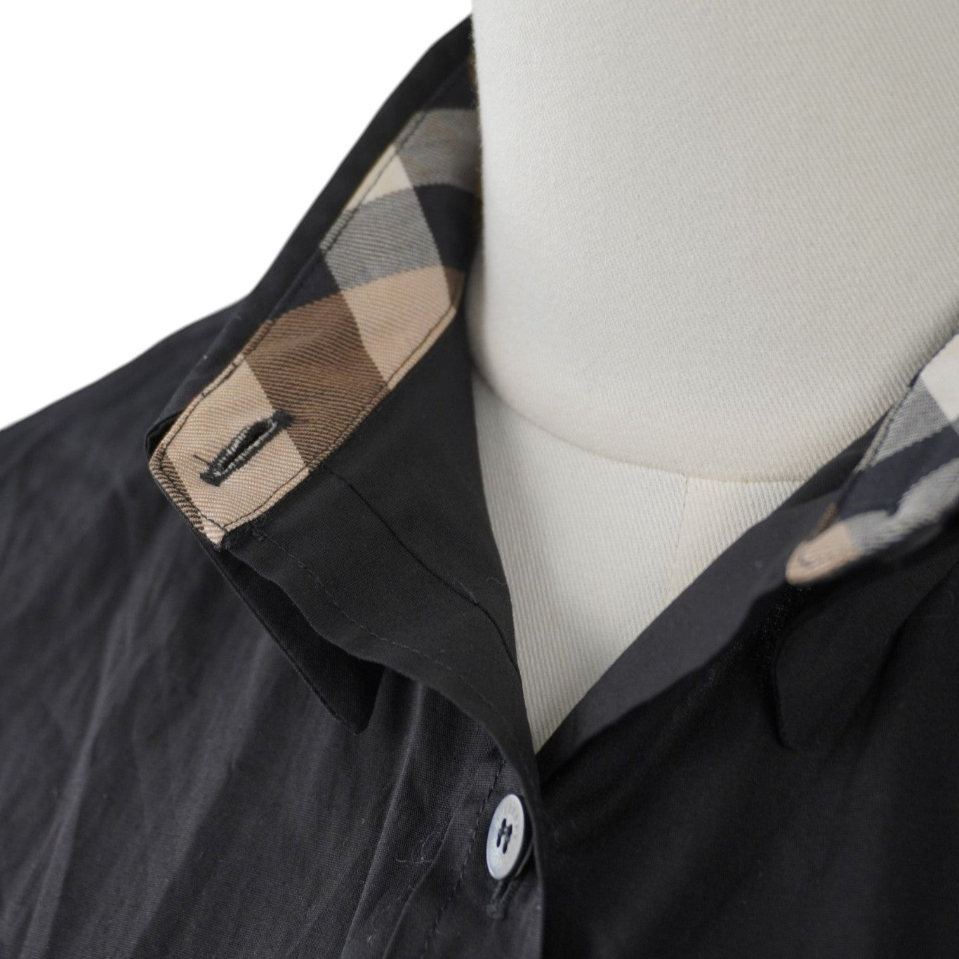 Particolare del colletto aperto della camicia che mostra la fodera interna con l'iconico motivo scozzese Vintage Check Burberry.
