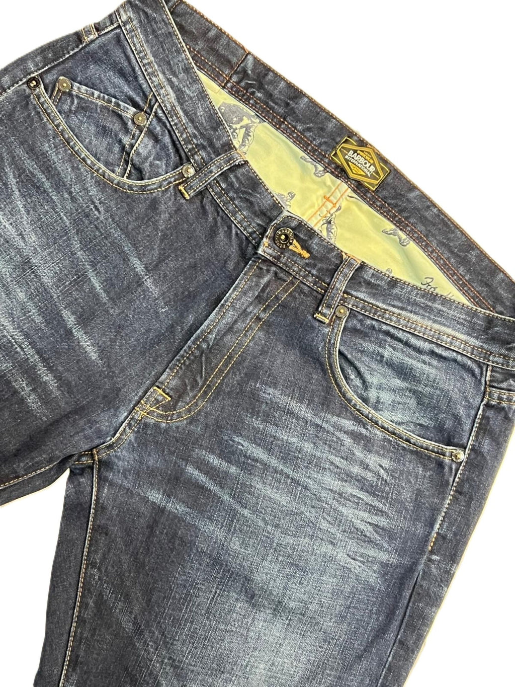 Inquadratura ravvicinata del denim dei jeans Barbour International focalizzata sulle venature e sulle scoloriture stile biker.