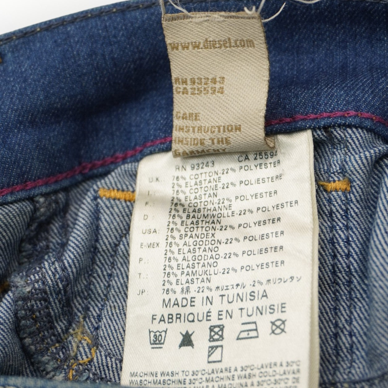 Primo piano delle etichette interne in tessuto con le istruzioni di lavaggio e la composizione del denim stretch.