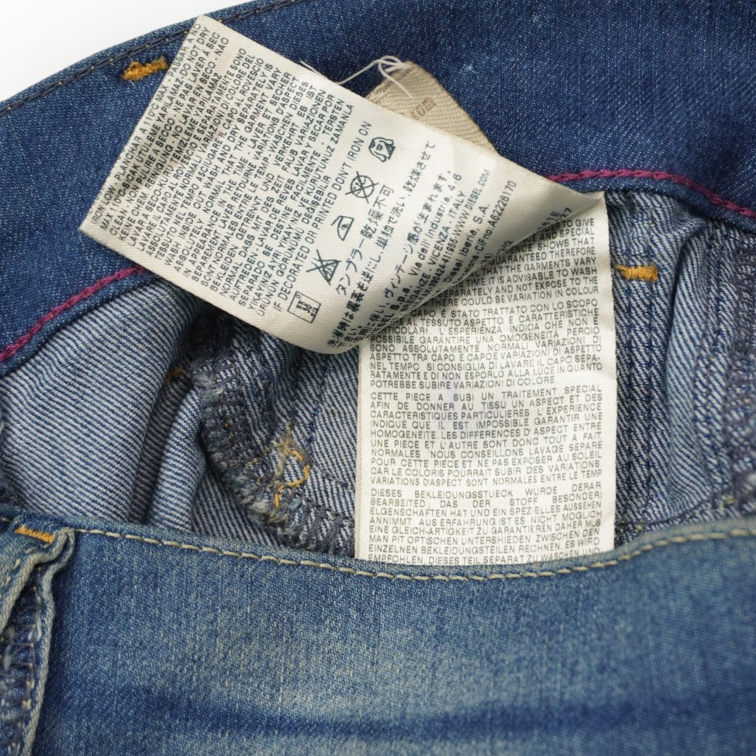 Primo piano delle etichette interne in tessuto con le istruzioni di lavaggio e la composizione del denim stretch.