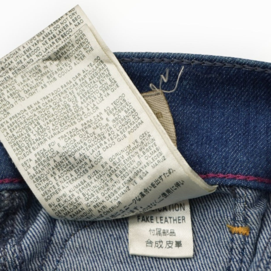Primo piano delle etichette interne in tessuto con le istruzioni di lavaggio e la composizione del denim stretch.