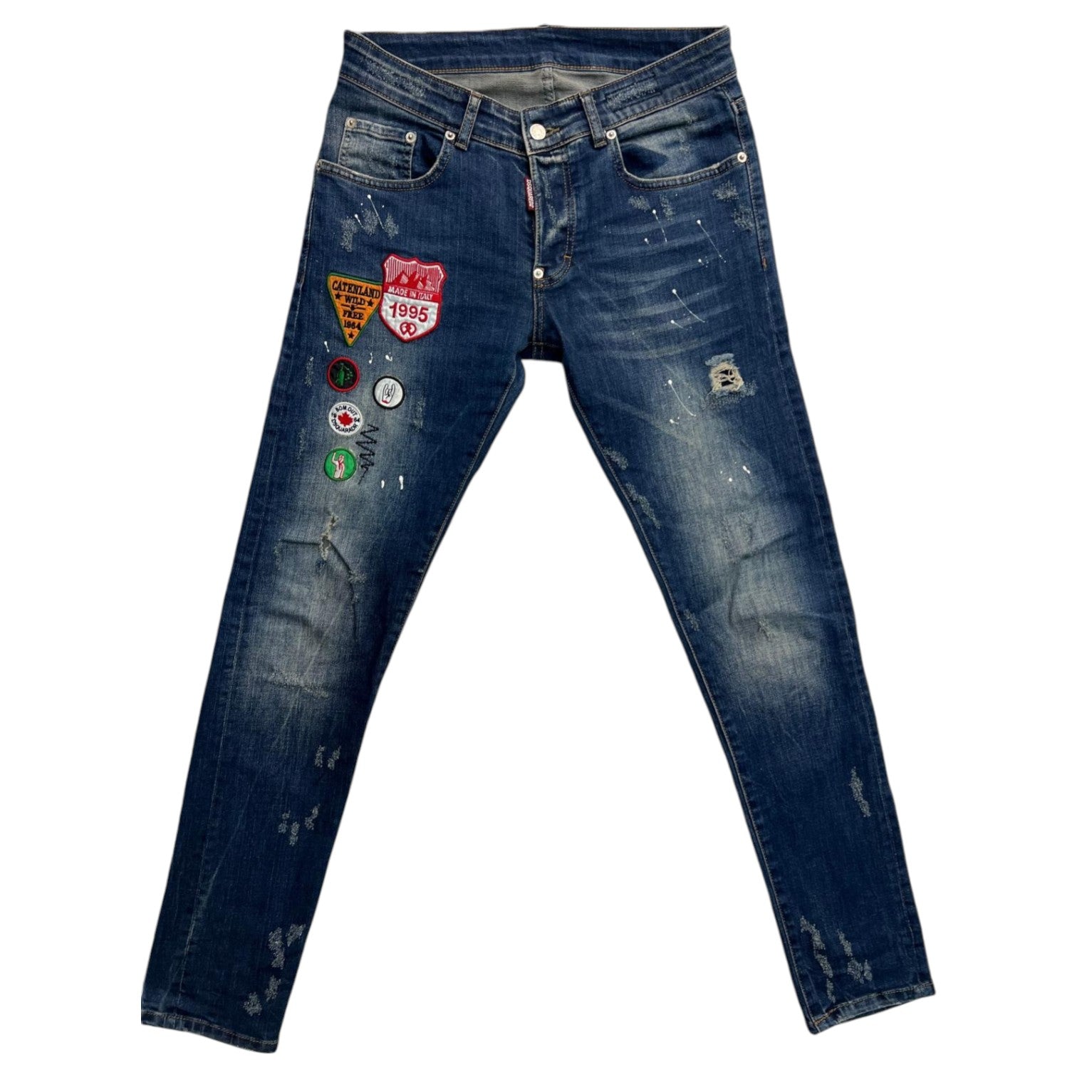Vista frontale completa dei jeans DSquared2 blu scuro con multi-patch ricamati sulla gamba destra.
