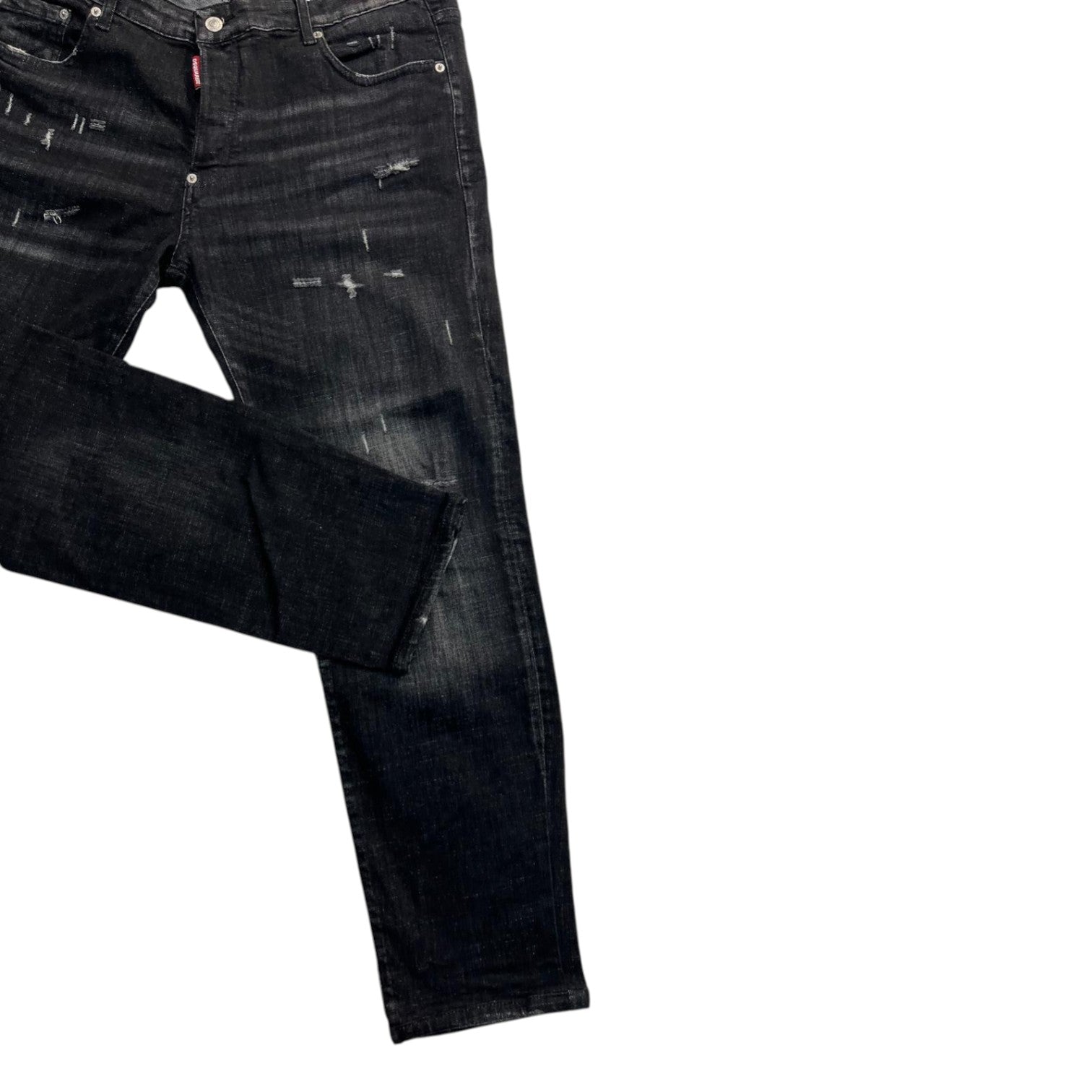  Dettaglio della gamba affusolata dei jeans neri Dsquared2 disposti in diagonale.