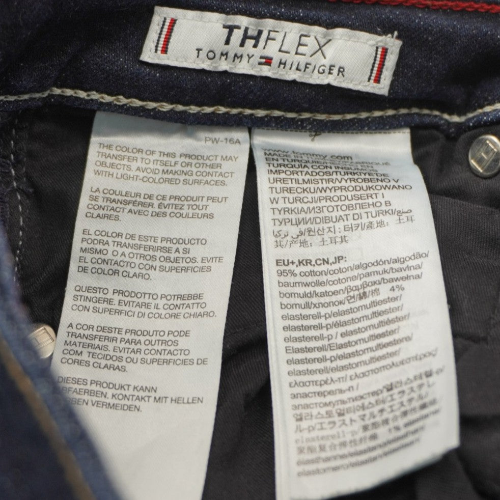 Dettaglio delle etichette interne bianche con le istruzioni di lavaggio e la composizione del tessuto denim stretch.