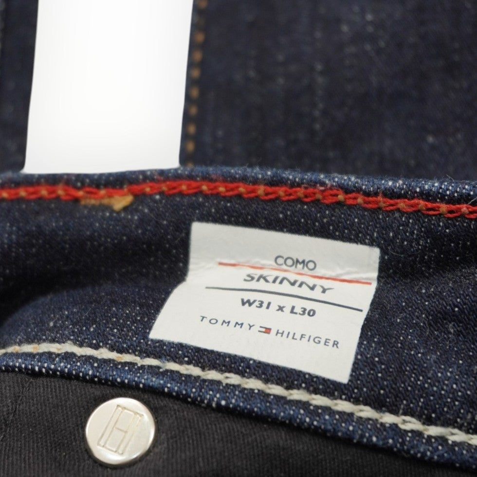 Primo piano dell'etichetta rettangolare in tessuto cucita all'interno della vita dei jeans Tommy Hilfiger.