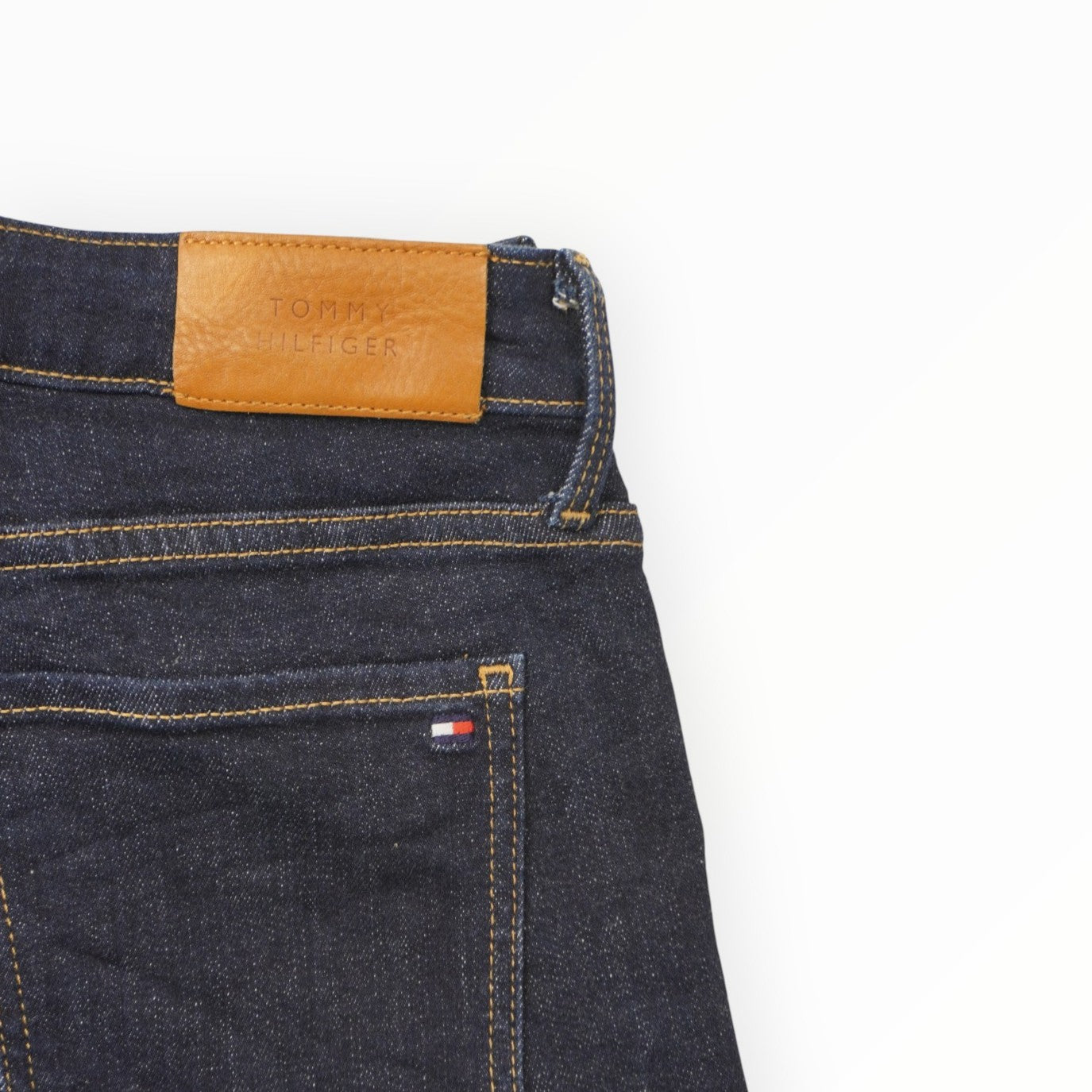 Dettaglio del patch in pelle marrone con logo Tommy Hilfiger sulla parte posteriore della vita.