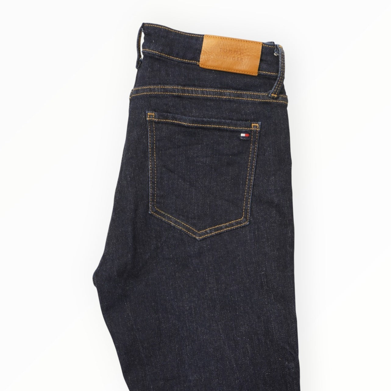 Primo piano di una tasca posteriore dei jeans Tommy Hilfiger con cuciture a contrasto e ricamo iconico.