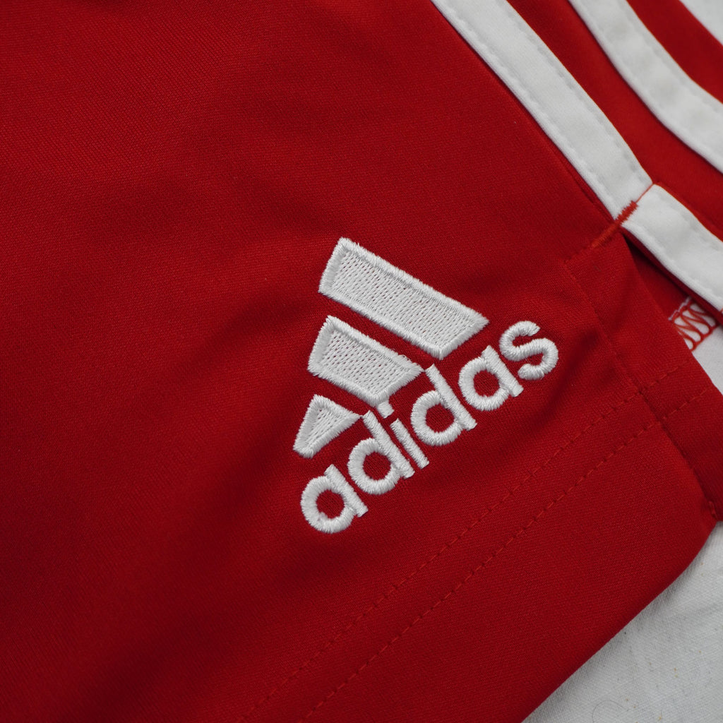 Dettaglio del logo adidas Performance ricamato in bianco ad alta densità sul tessuto tecnico rosso.