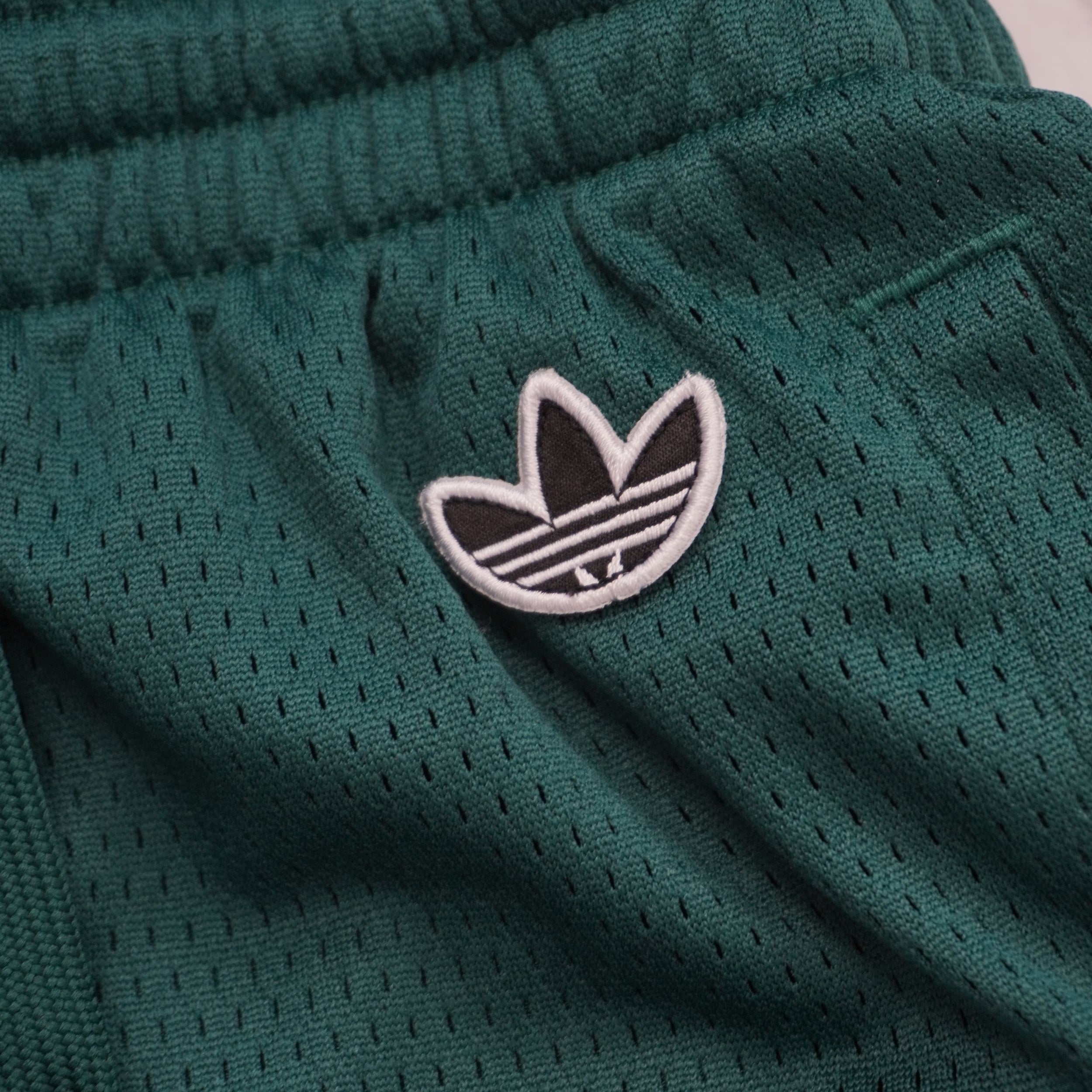 Primo piano del logo Trefoil (Trifoglio) di adidas Originals ricamato su patch circolare e applicato sul fronte degli shorts.