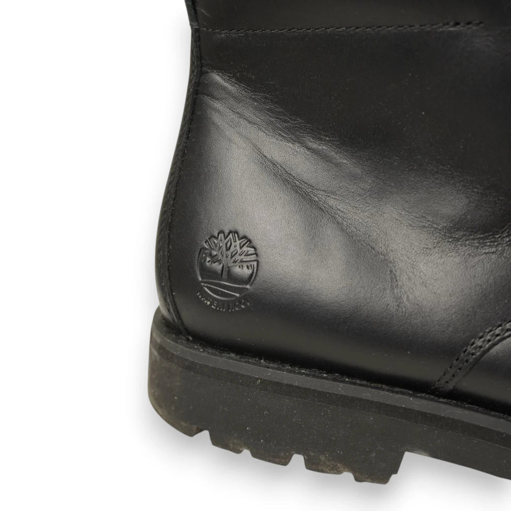 Primo piano del logo dell'albero Timberland impresso a fuoco sulla pelle nera laterale vicino alla suola a carrarmato.