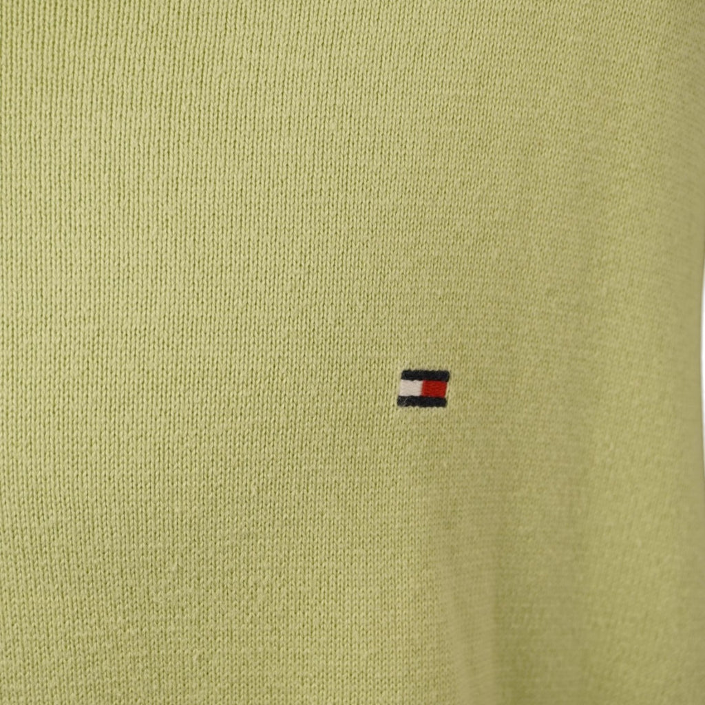 Dettaglio del piccolo logo della bandierina Tommy Hilfiger ricamato sul petto del maglione.