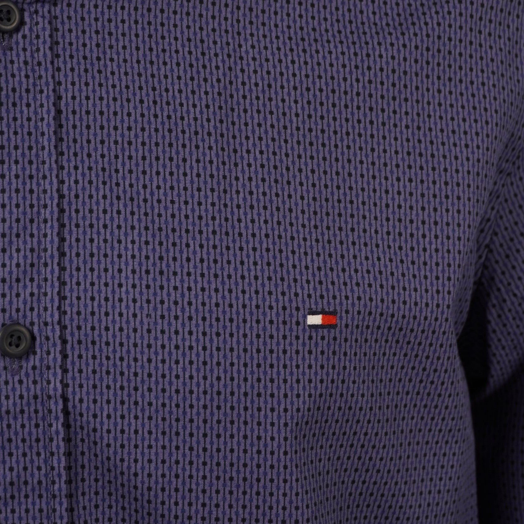 Dettaglio macro del mini logo a bandierina Tommy Hilfiger ricamato sul petto della camicia