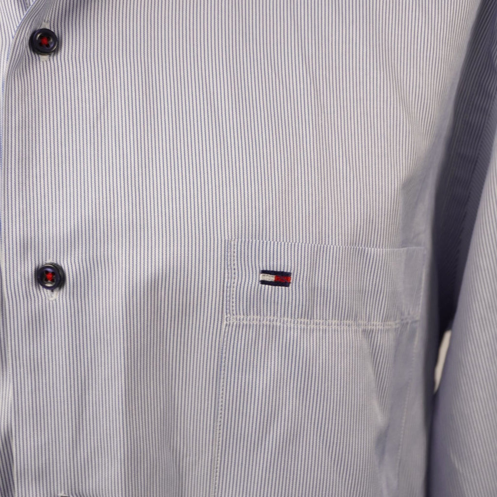 Inquadratura macro del logo a bandierina Tommy Hilfiger ricamato sul petto della camicia gessata