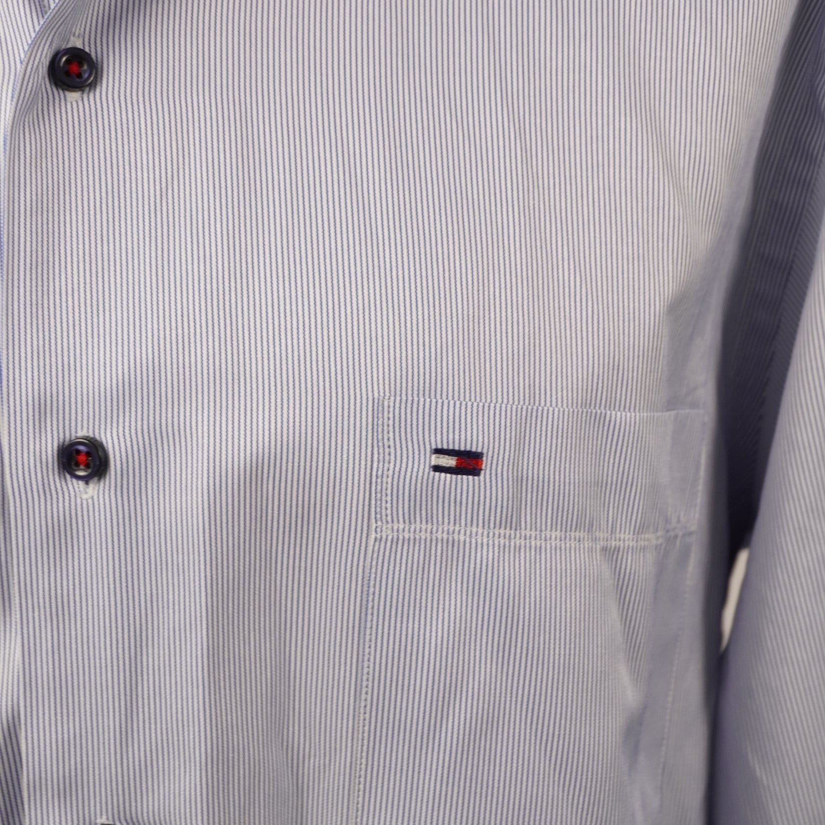 Inquadratura macro del logo a bandierina Tommy Hilfiger ricamato sul petto della camicia gessata