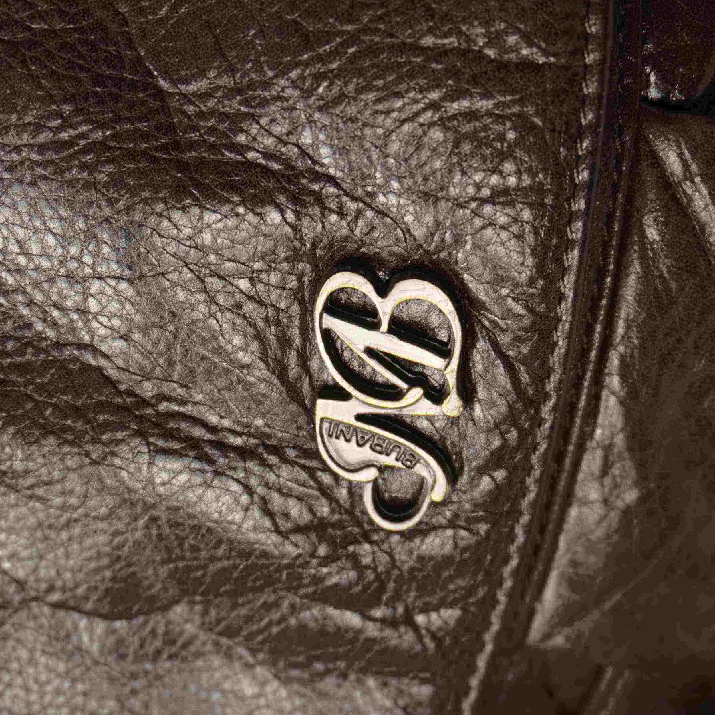 Primo piano del logo metallico dorato con le iniziali MB intrecciate sulla patta in pelle marrone.