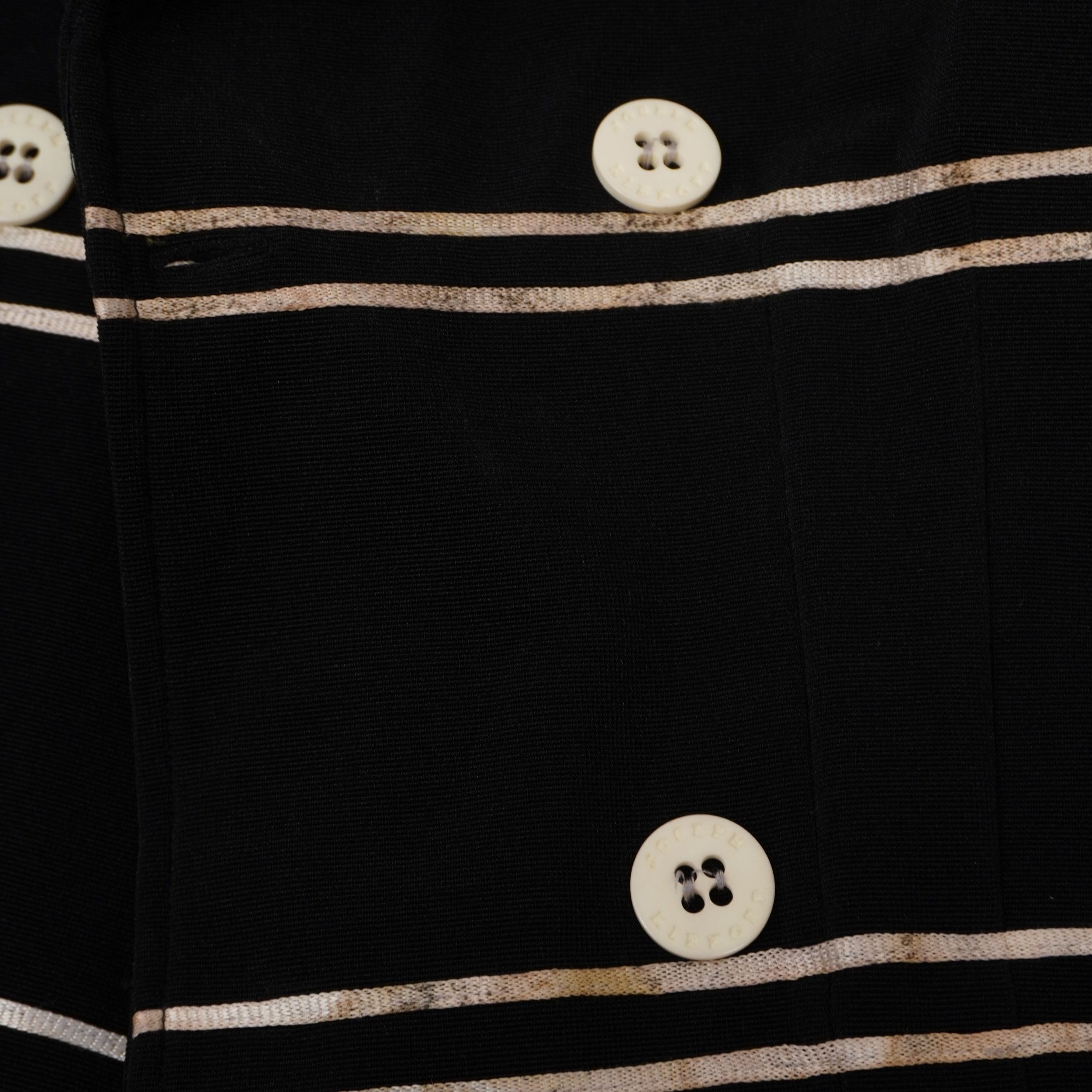 Primo piano dei bottoni chiari a contrasto e delle strisce bianche con piccoli difetti di colorazione diffusi.