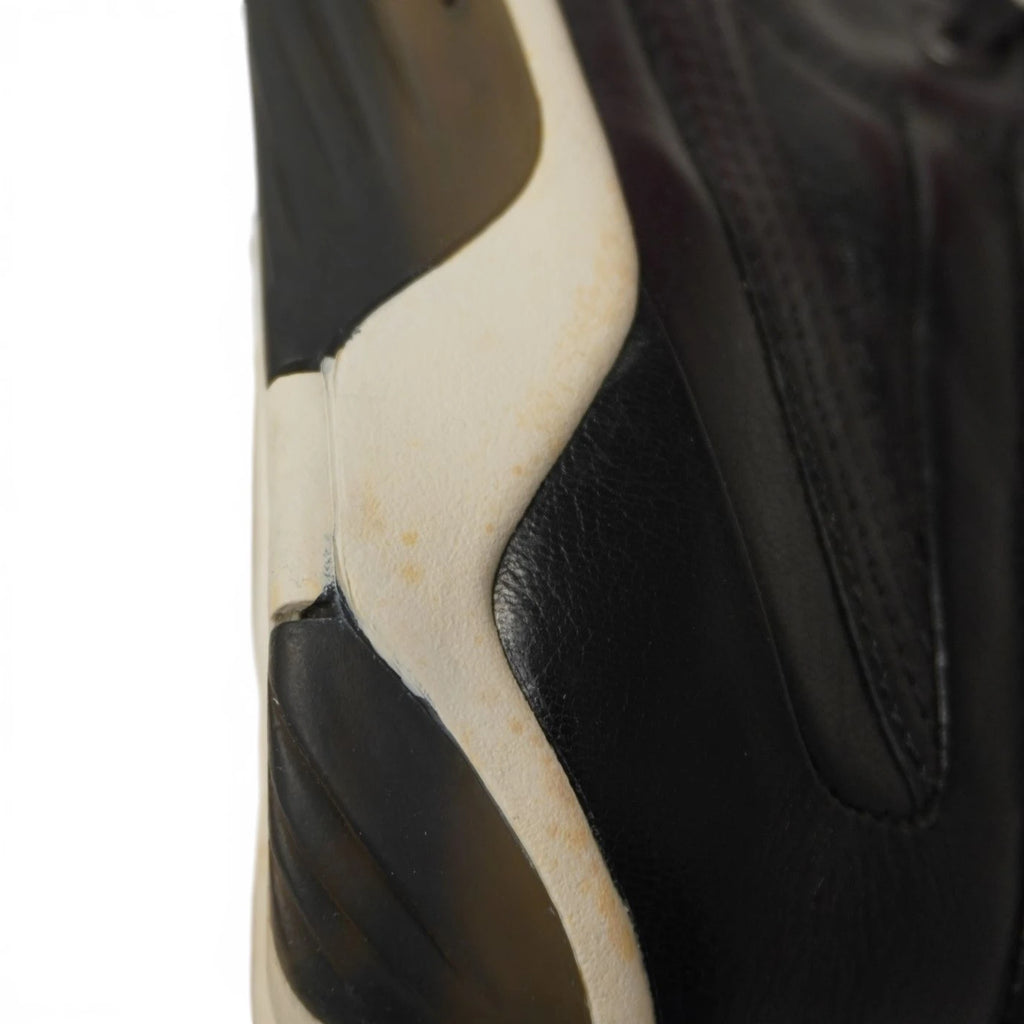 Dettaglio macro puntale in metallo cromato con incisione Alexander McQueen su laccio nero