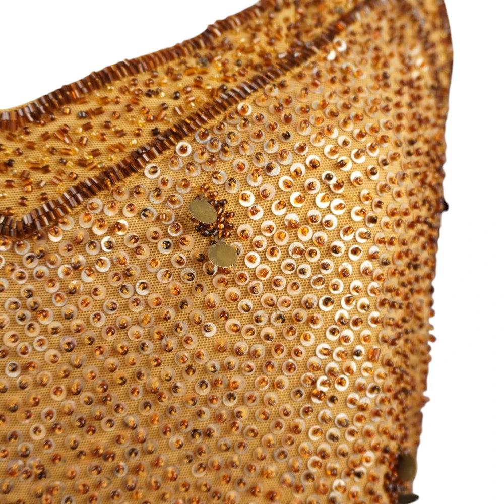 Inquadratura ravvicinata del fitto ricamo artigianale con micropaillettes e applicazioni di perline tridimensionali pendenti.