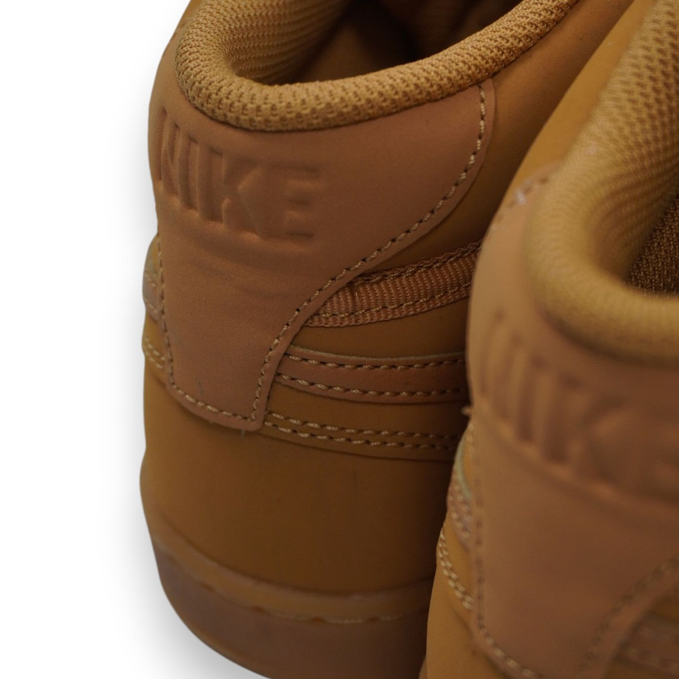 Particolare ravvicinato del logo Nike impresso a caldo in rilievo sul controtallone marrone