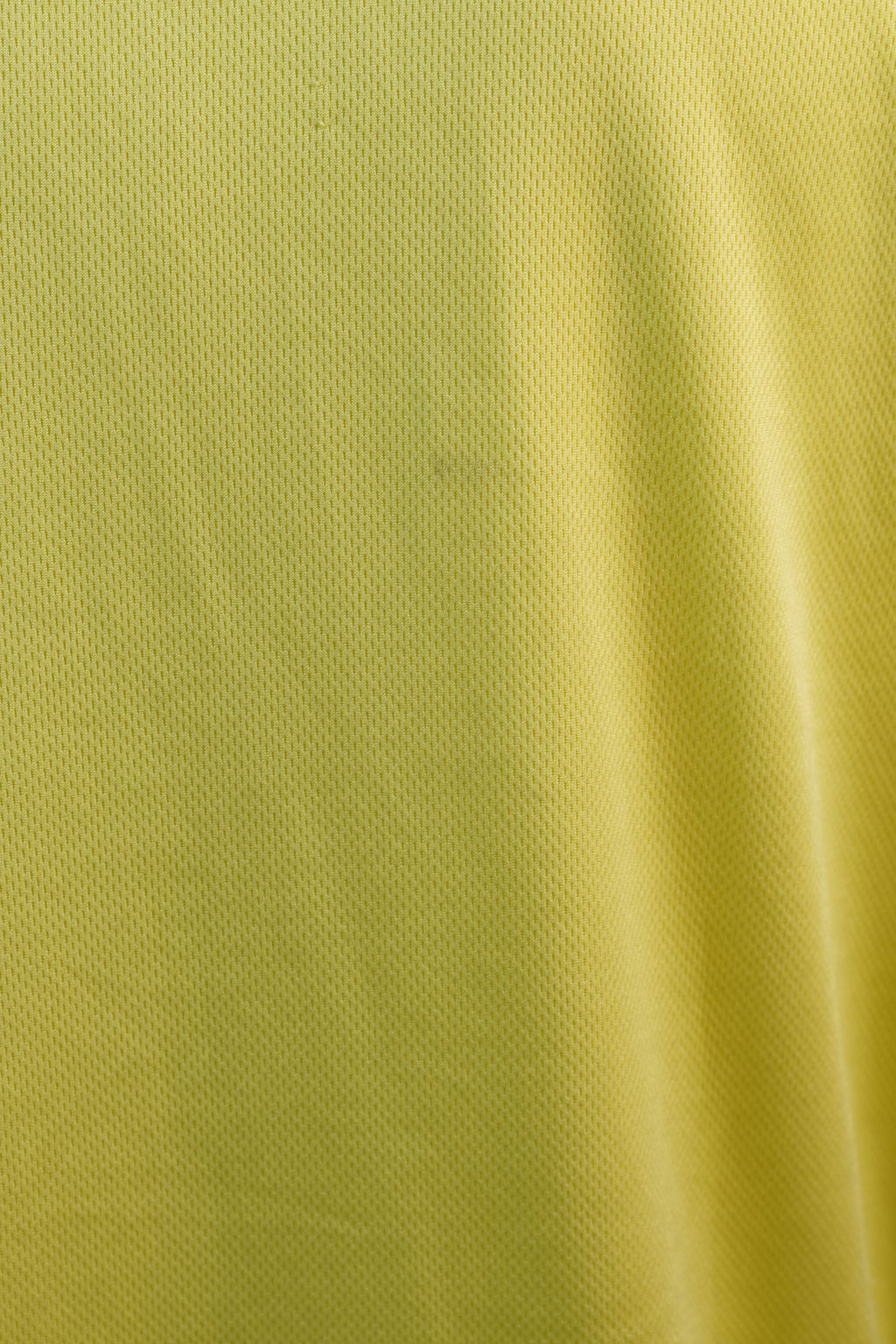 Inquadratura macro ravvicinata della superficie liscia e leggera del tessuto sportivo giallo della maglia da baseball.
