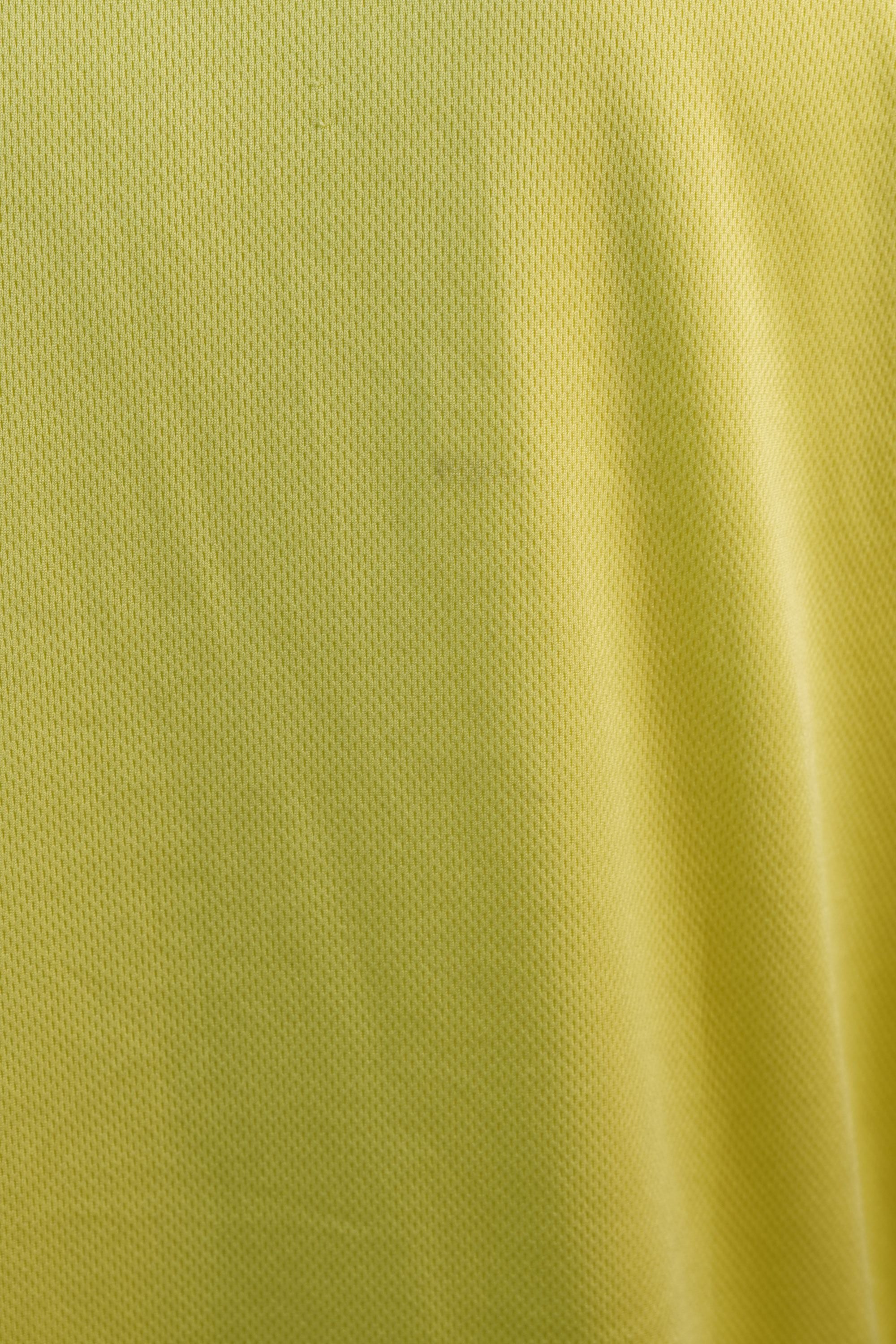 Inquadratura macro ravvicinata della superficie liscia e leggera del tessuto sportivo giallo della maglia da baseball.
