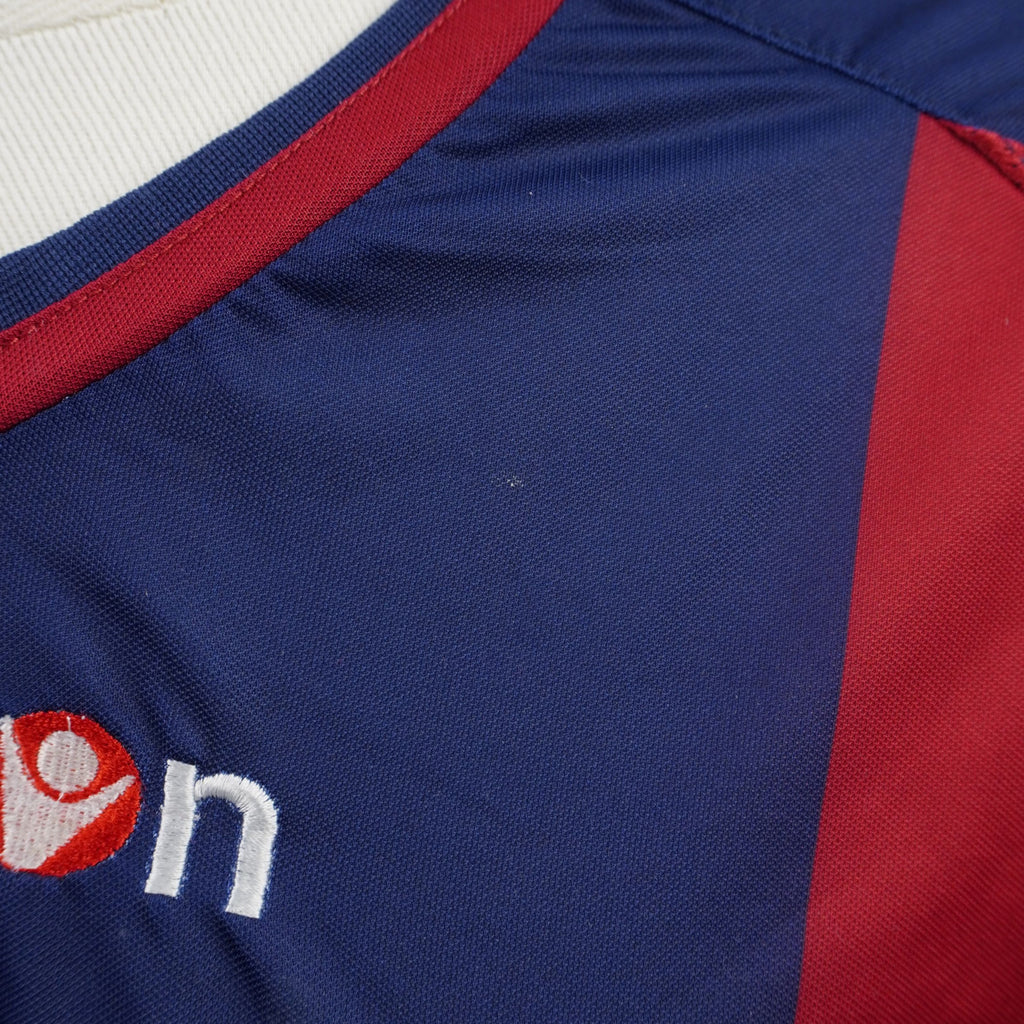 Particolare del colletto a V bicolore rosso e blu della maglia del Bologna con cuciture tecniche elasticizzate
