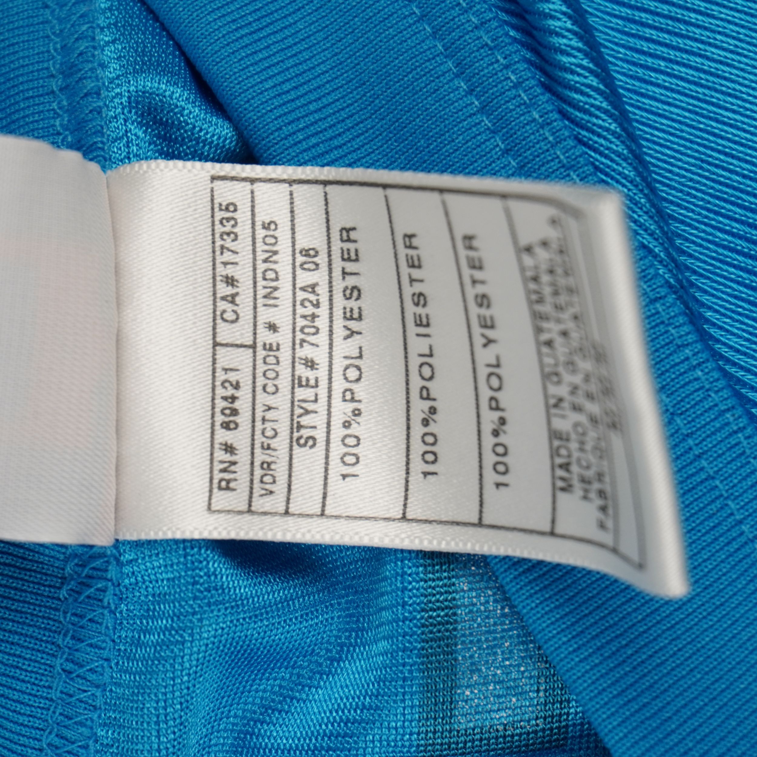 Etichetta interna in tessuto con codice RN69421, Style 7042A e indicazioni di produzione in Guatemala.