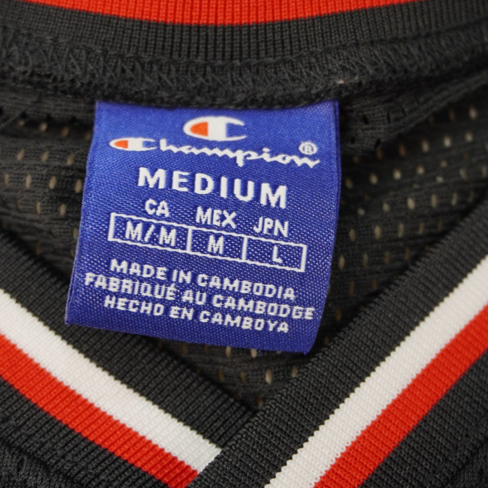 Dettaglio dell'etichetta interna blu cucita sul colletto che mostra il brand Champion e la taglia Medium (M).
