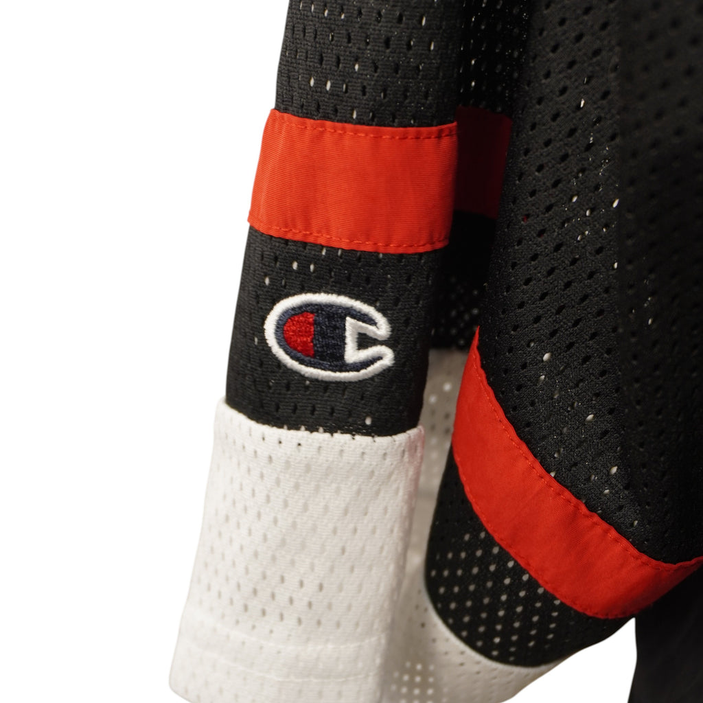 Dettaglio ravvicinato della classica patch con il logo "C" di Champion applicata sulla manica della jersey.