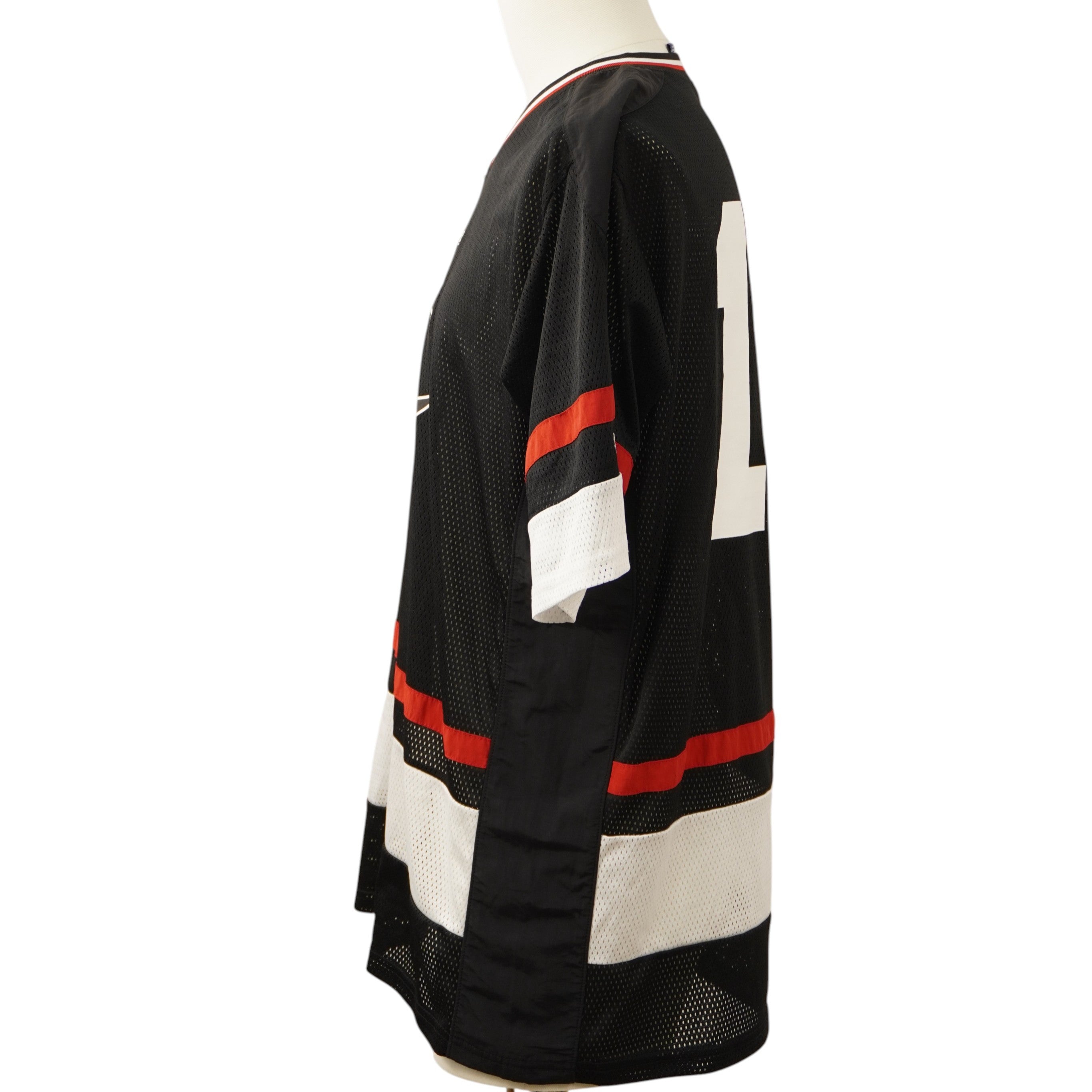 Vista laterale della maglia da gioco Champion che mostra il taglio relaxed delle maniche e i dettagli tricolore.