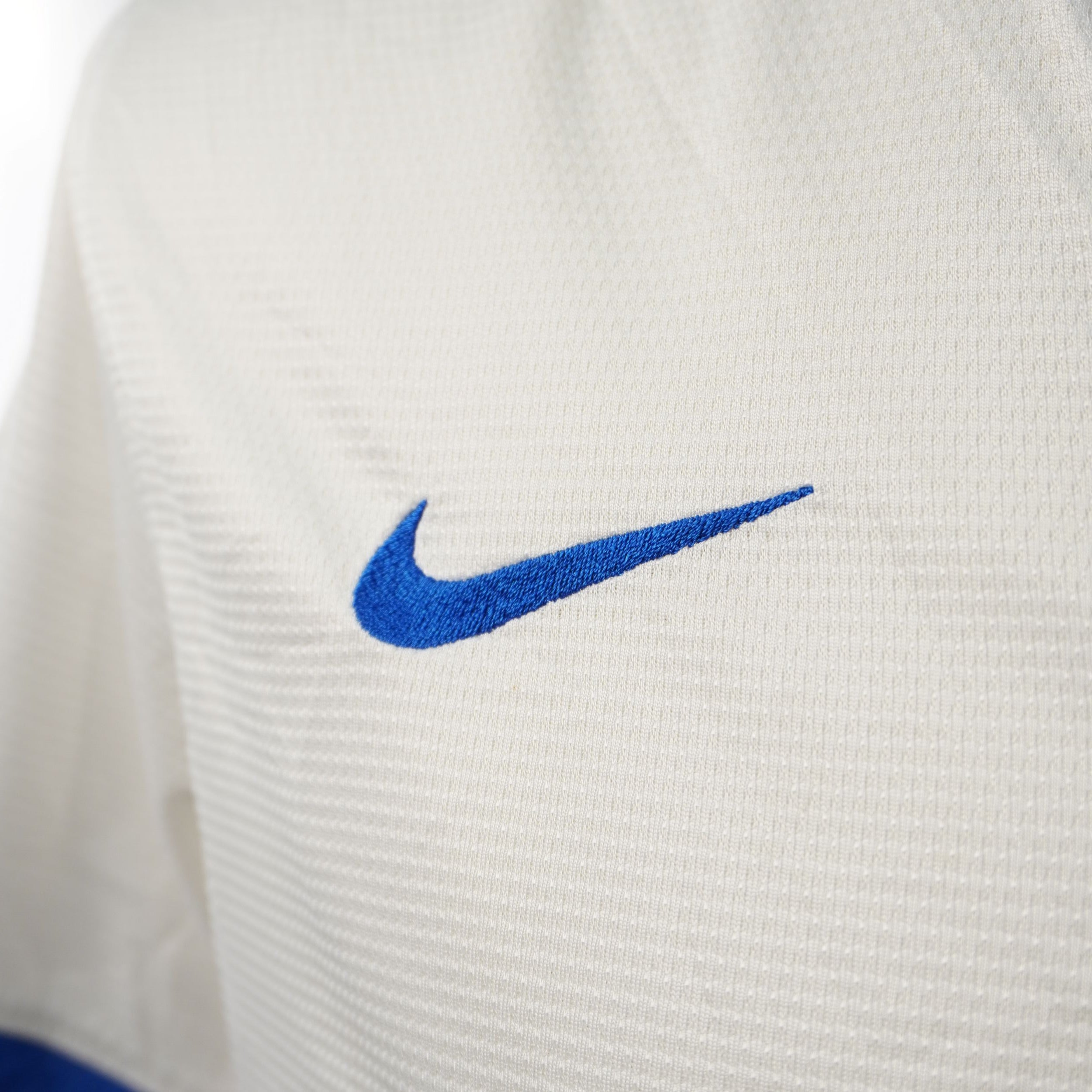 Dettaglio del logo Nike Swoosh ricamato in blu sulla maglia bianca dell'Inter.