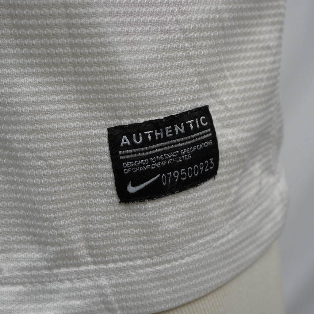 Dettaglio della patch nera rettangolare Nike Authentic con numero di serie cucita sul fondo della maglia.