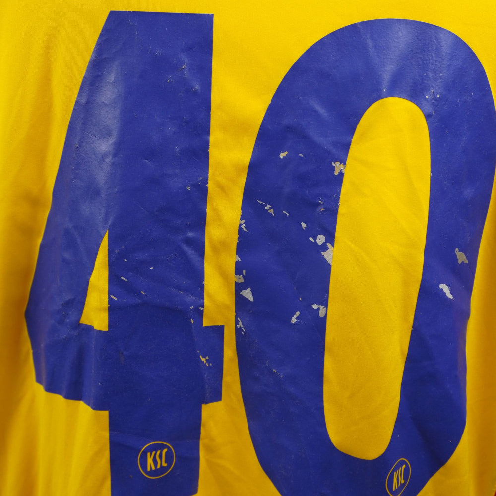 Primo piano dei segni di cracking e screpolatura sul numero stampato blu del retro maglia.