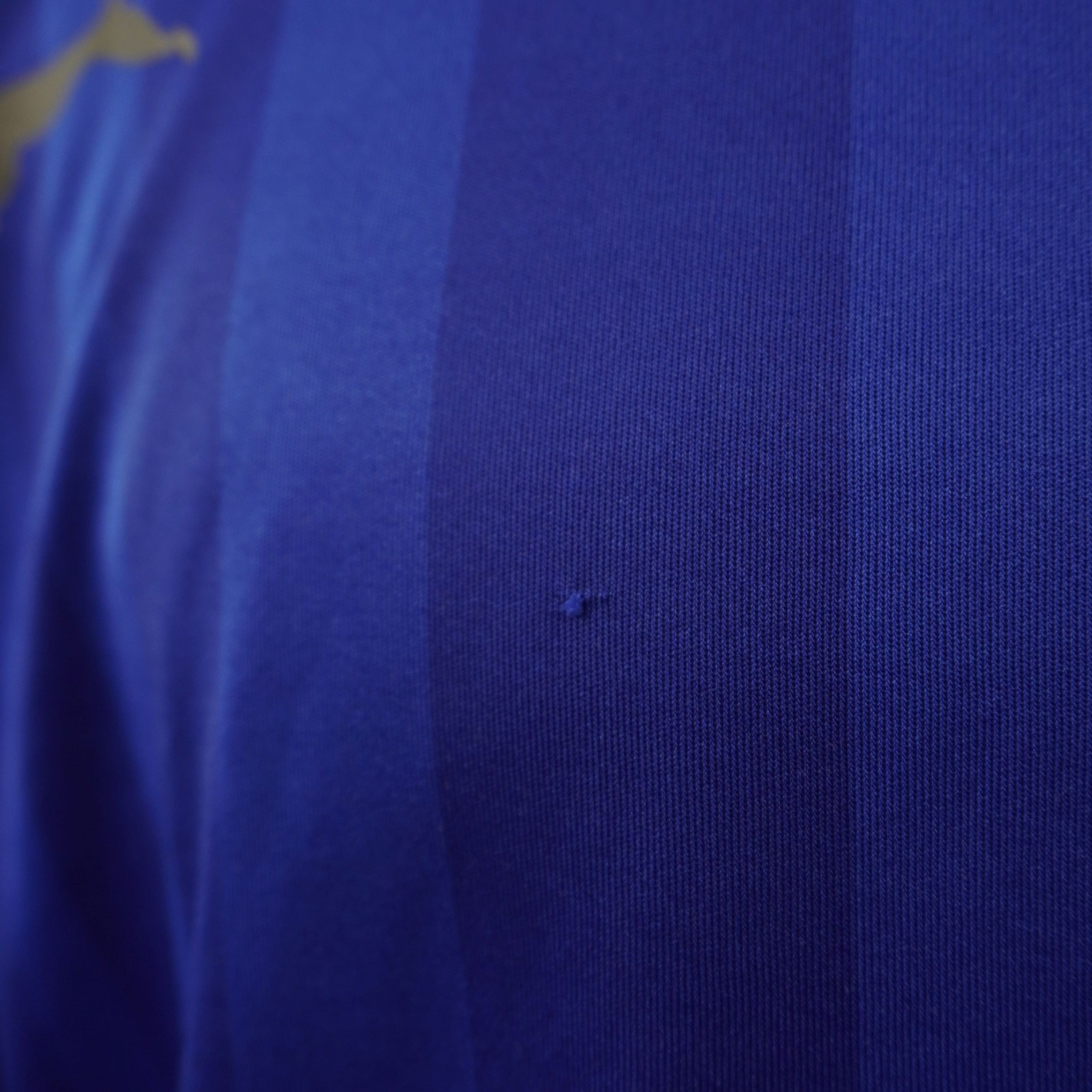 Macro foto del piccolo filo tirato (pull) sul tessuto jacquard blu della maglia.