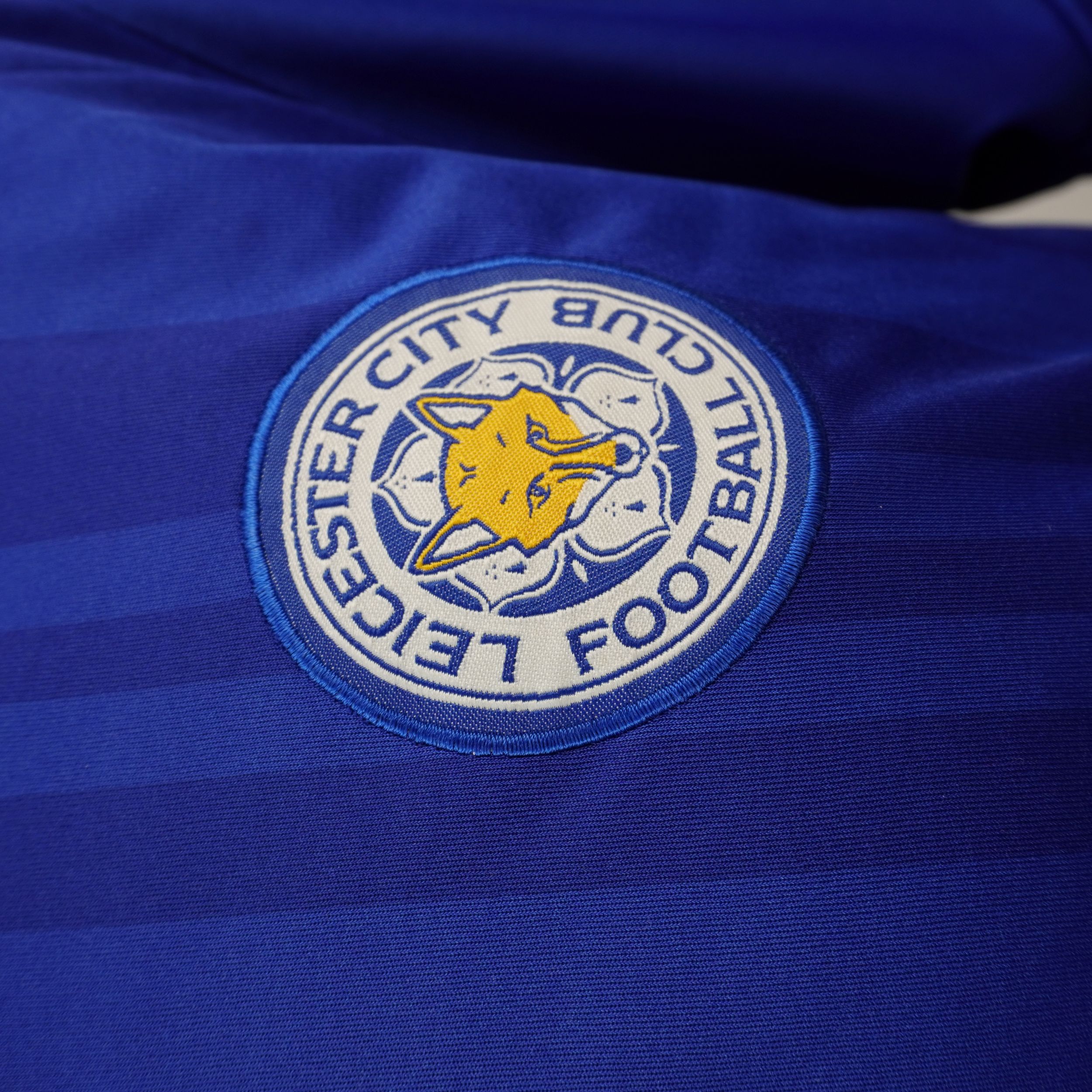 Primo piano dello stemma ufficiale ricamato del Leicester City Football Club sulla maglia.