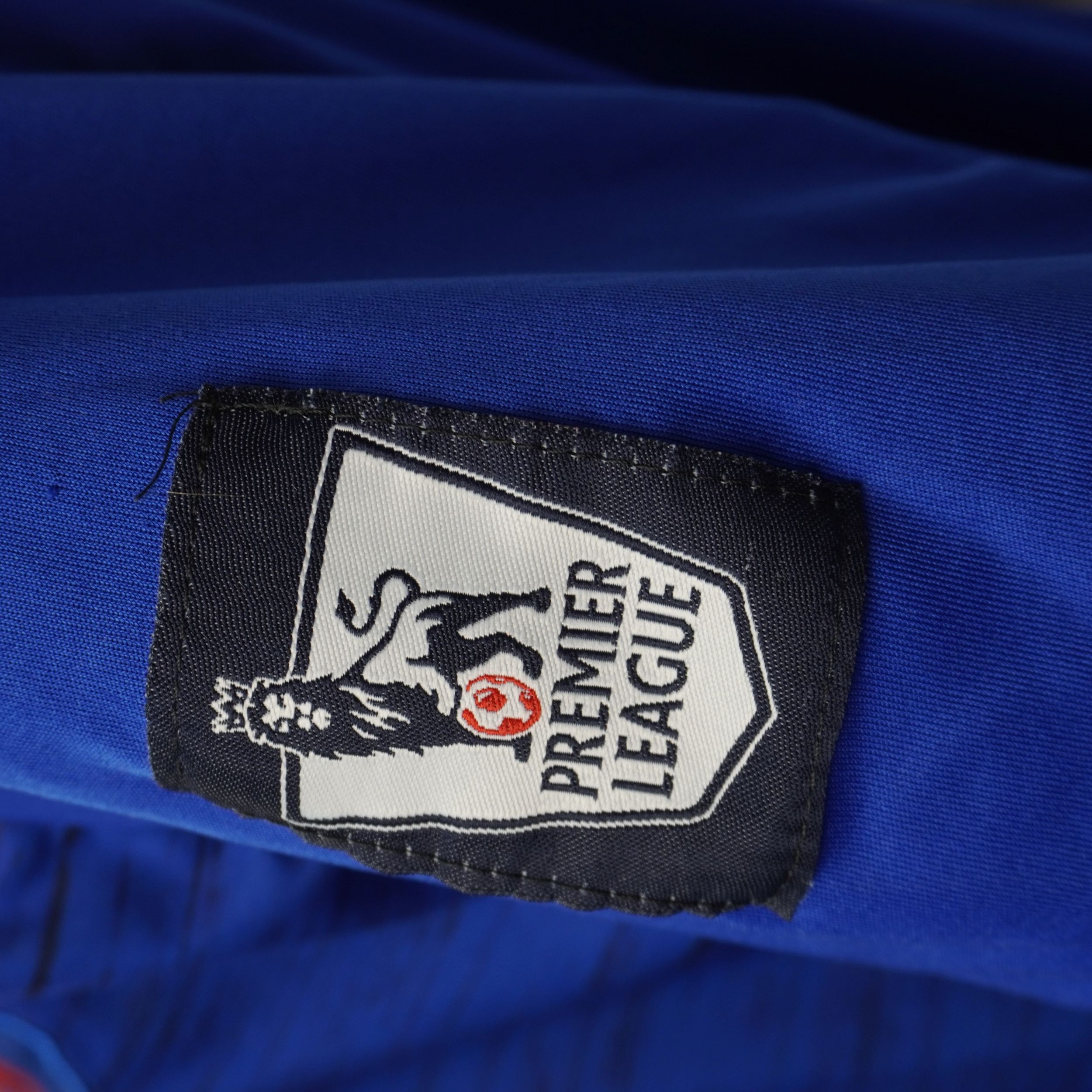 Primo piano della patch ufficiale della Premier League applicata sulla manica della maglia.